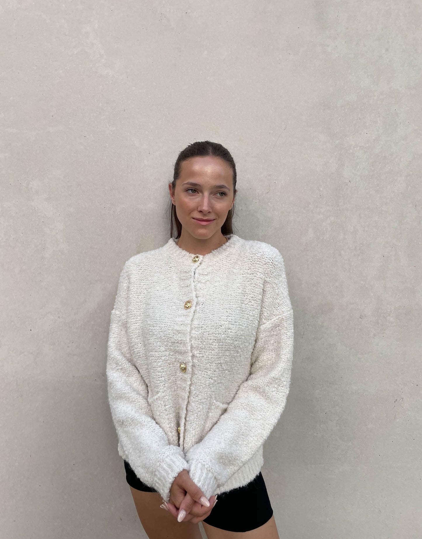 Frau mit braunen Haaren trägt Boucle Jacke in wollweiß