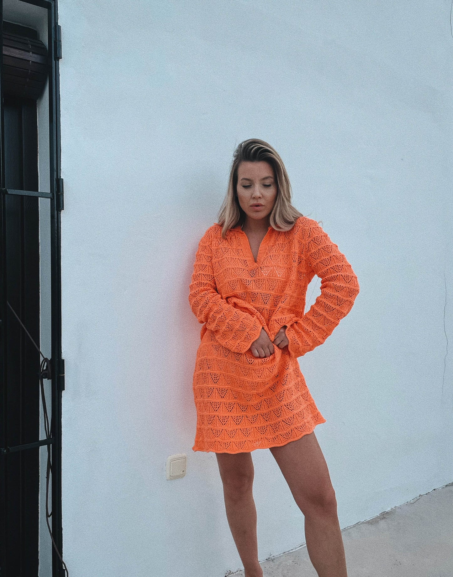Frau mit blonden Haaren trägt Häkelkleid in orange