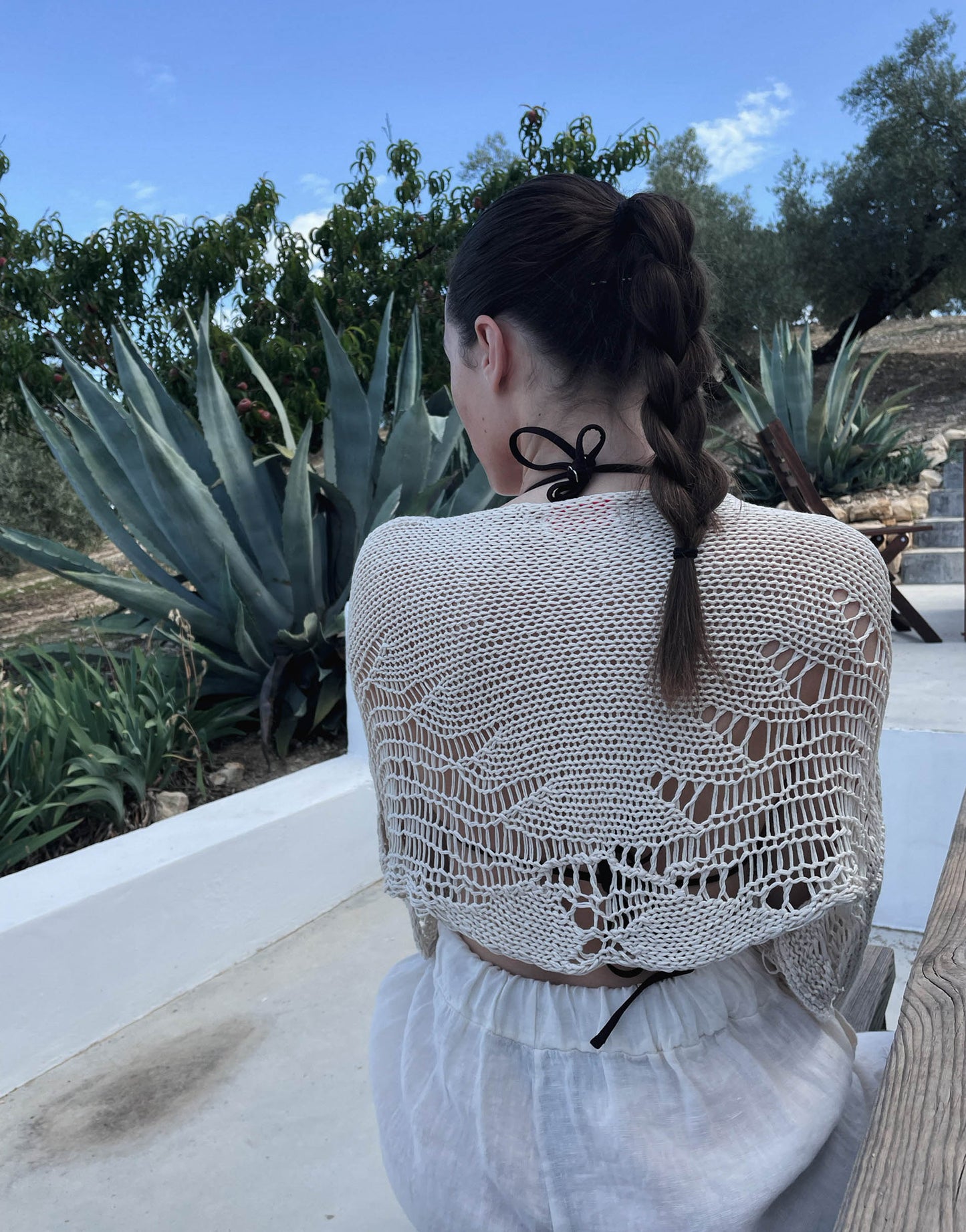 Frau mit brauen Haaren trägt Häkelpullover