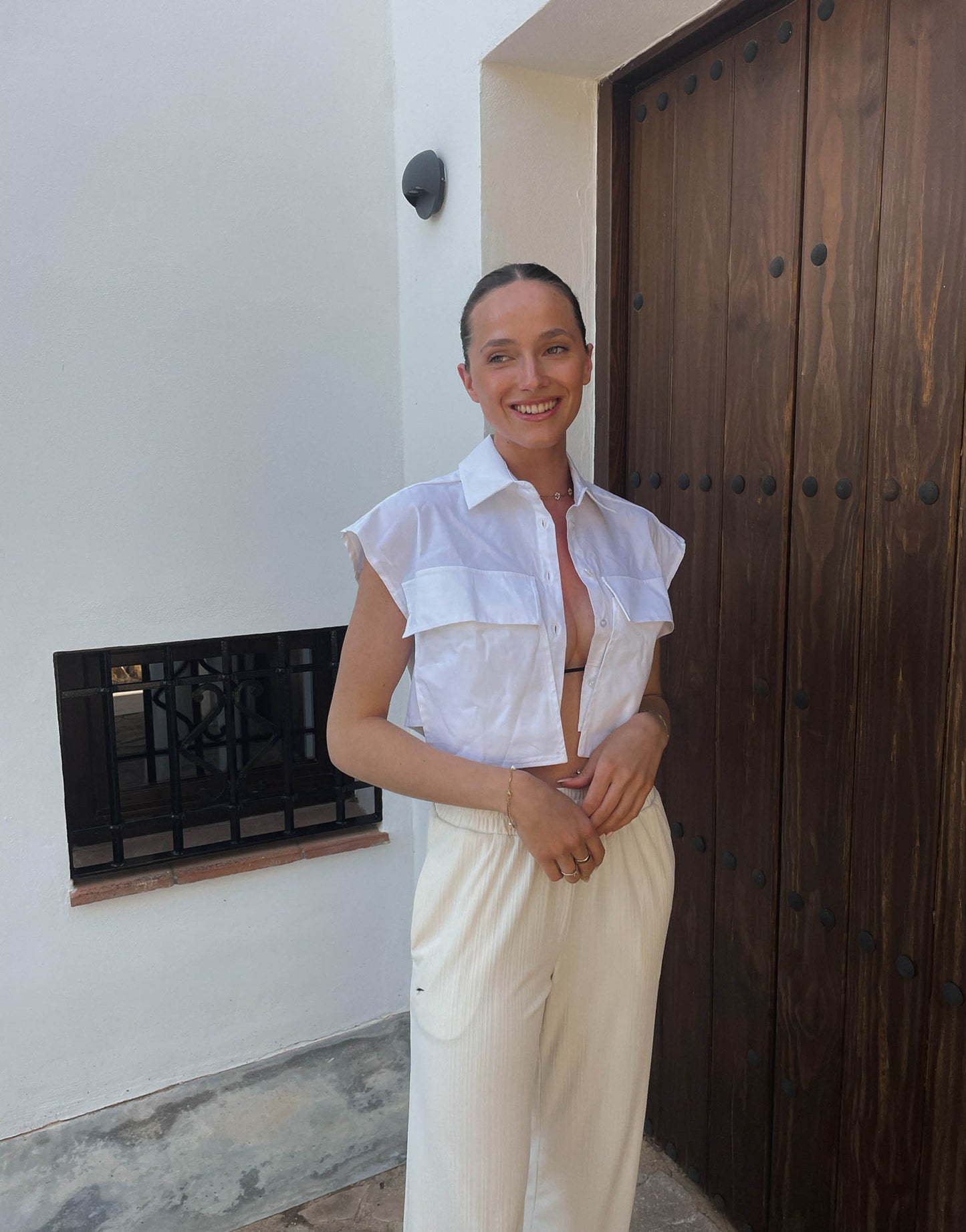 Frau mit brauen Haaren trägt cropped Hemdbluse mit überschnittenen Schultern