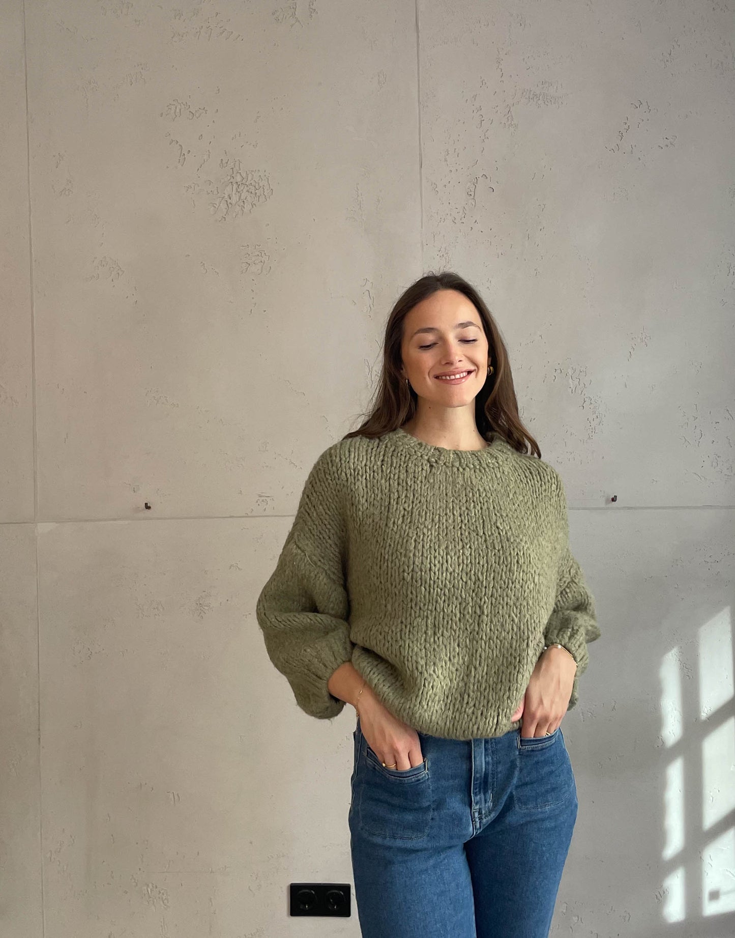 Frau mit brauen Haaren trägt kurzen Grobstrickpullover in khaki