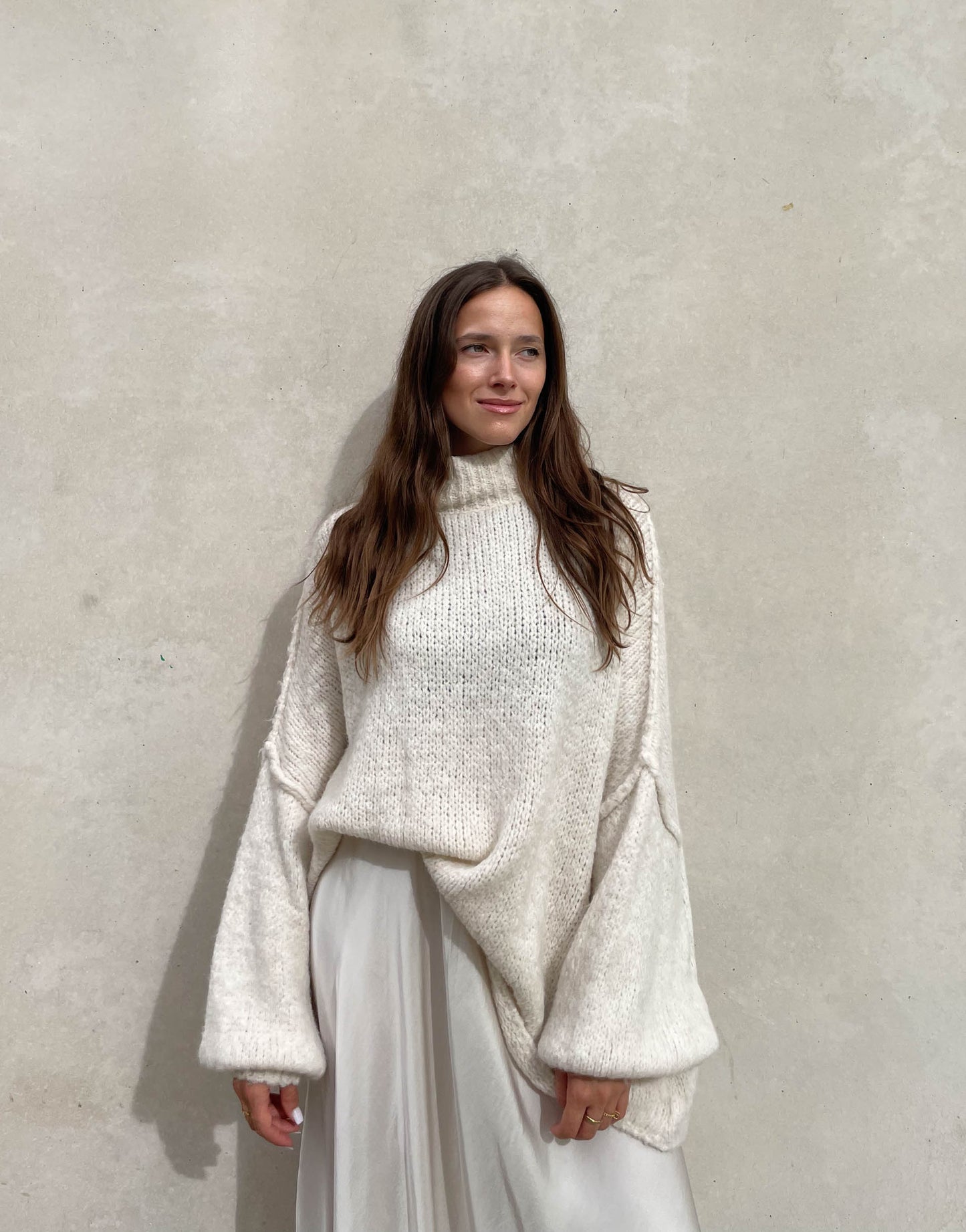 Frau mit brauen Haaren trägt oversize Pullover in beige