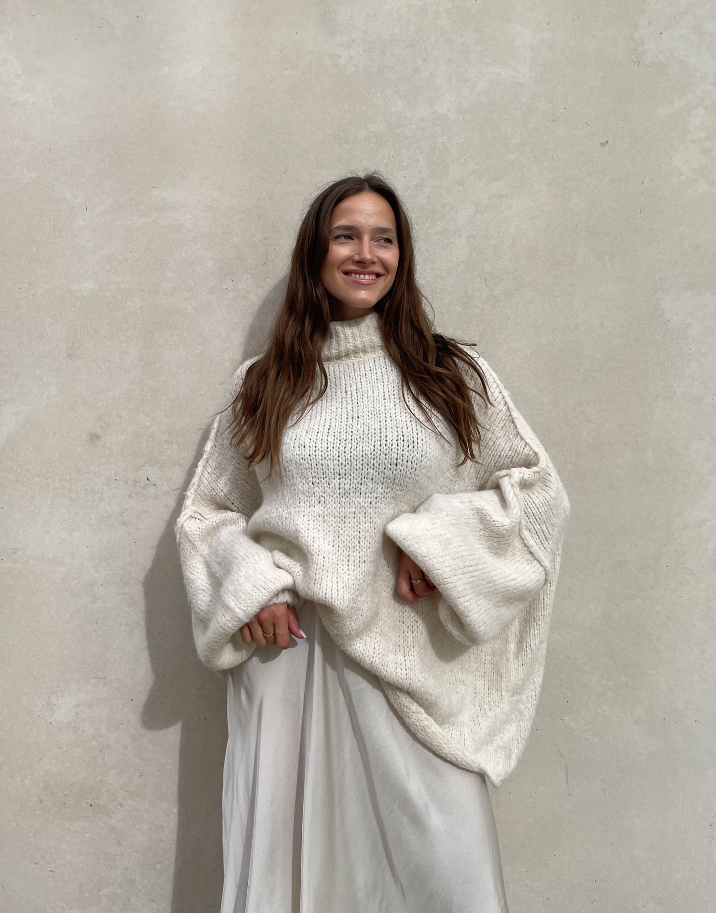 Frau mit brauen Haaren trägt oversize Pullover in beige