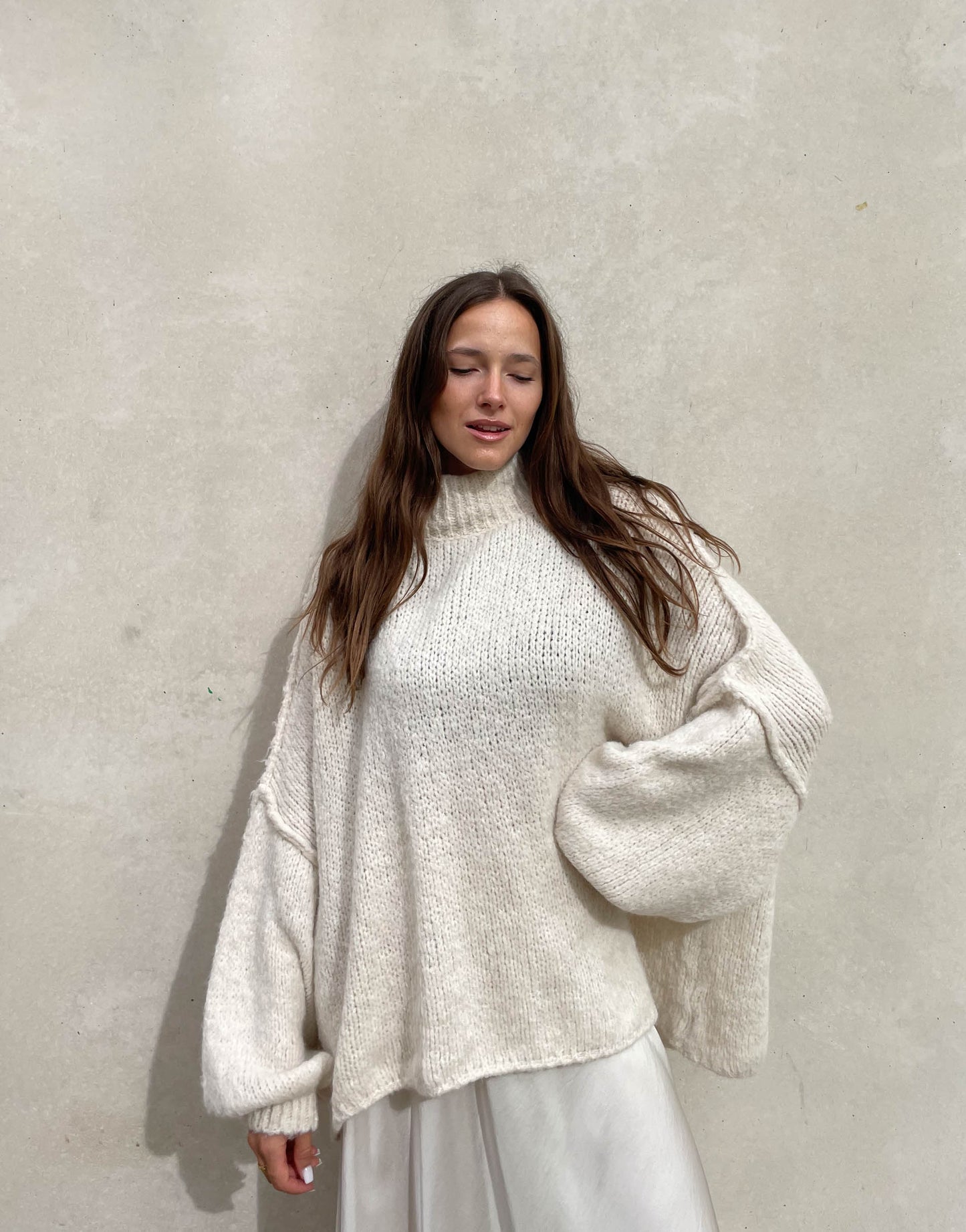 Frau mit brauen Haaren trägt oversize Pullover in beige