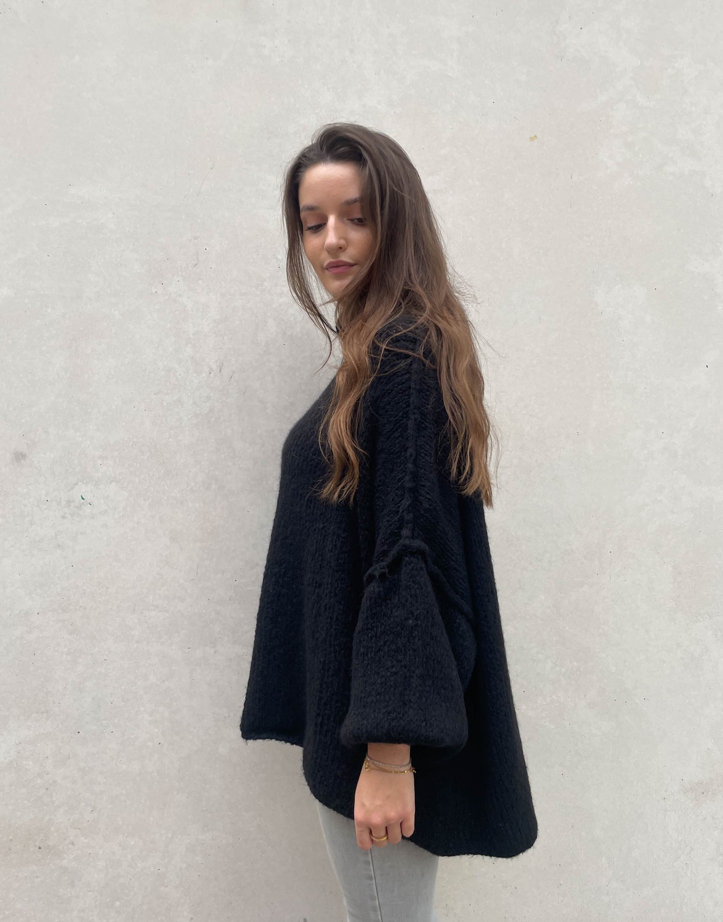Frau mit brauen Haaren trägt oversize Pullover in schwarz
