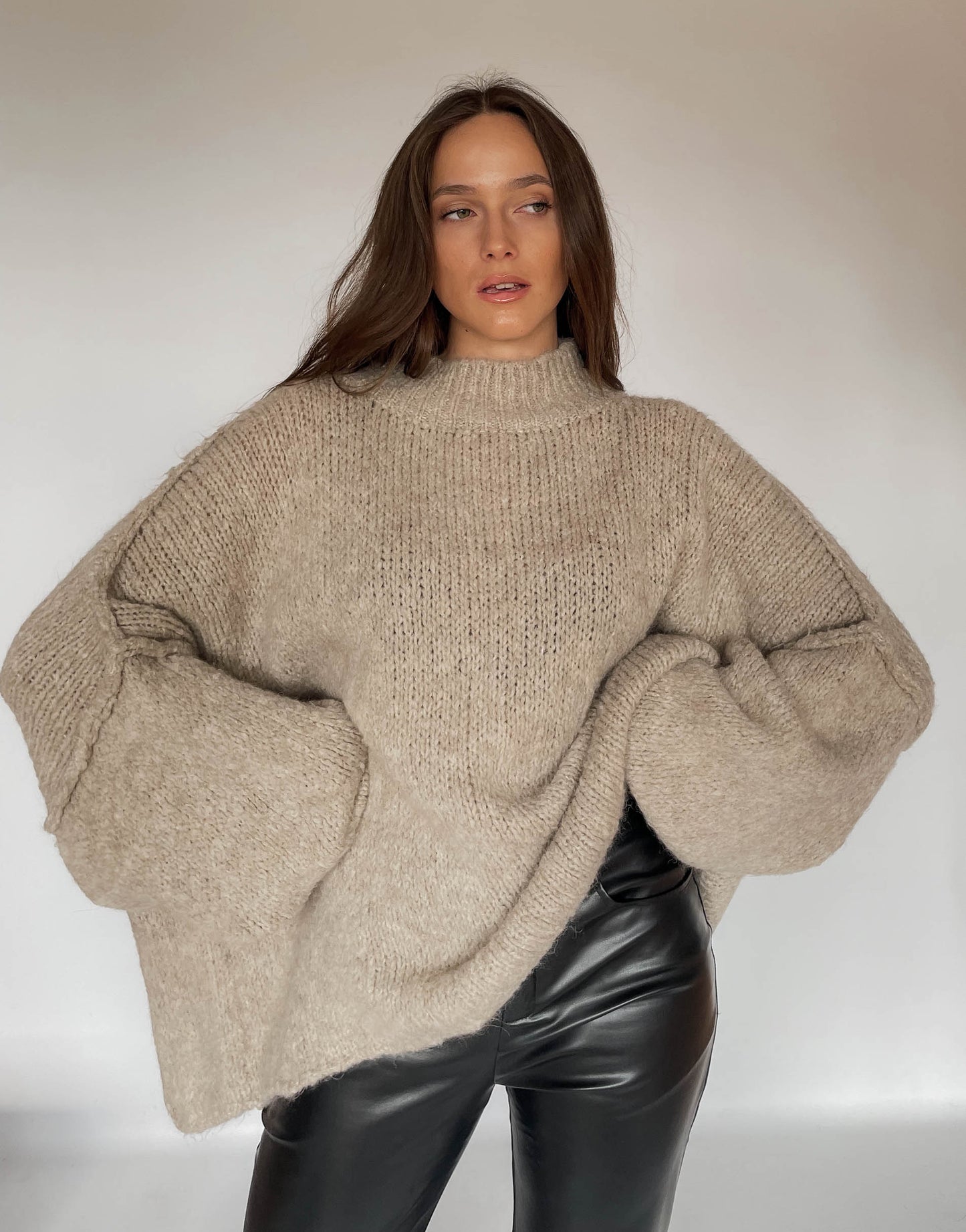 Frau mit brauen Haaren trägt oversize Pullover in taupe