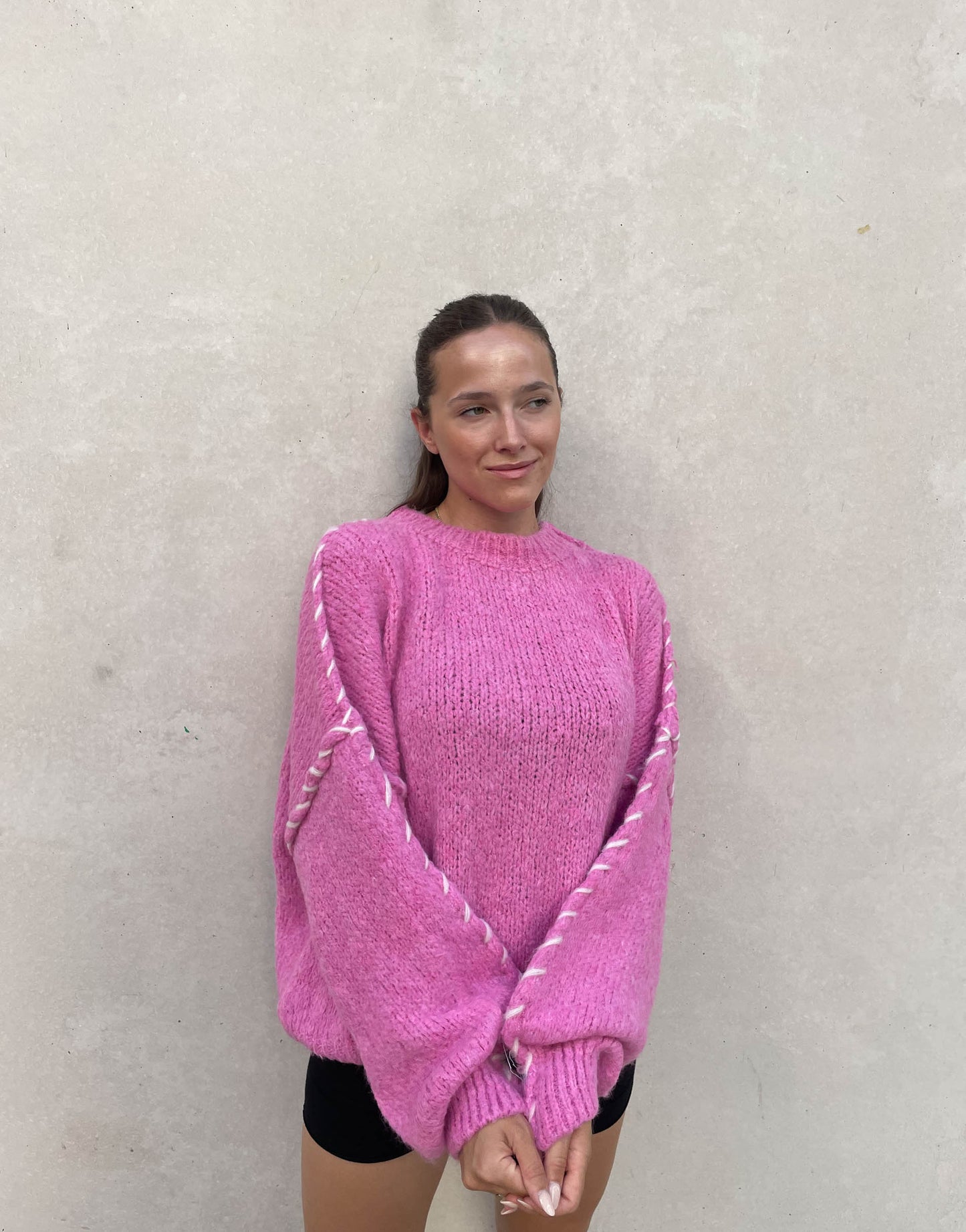 Frau mit brauen Haaren trägt Oversize Pullover in Pink