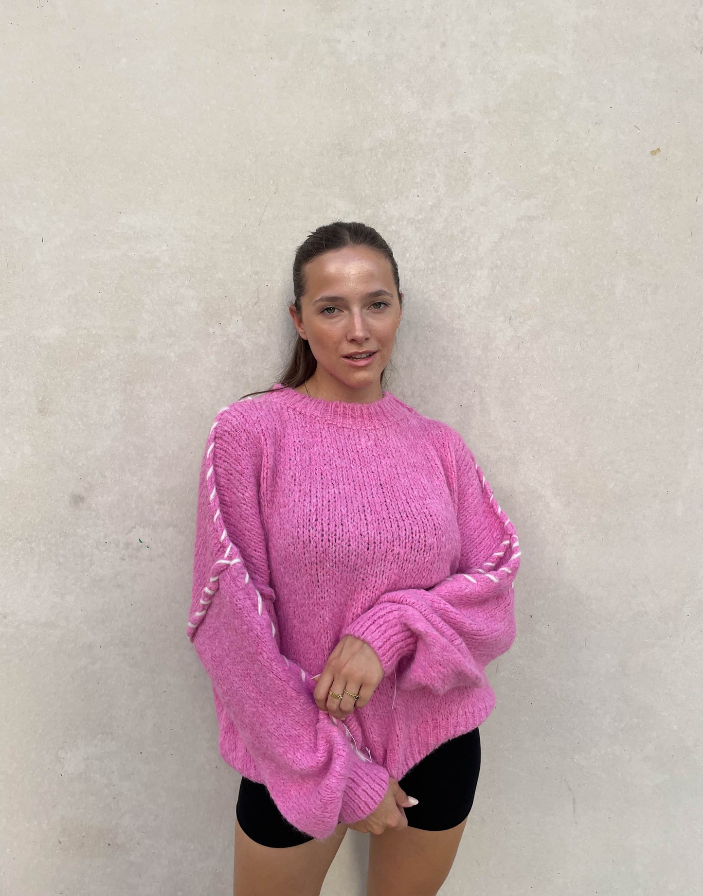 Frau mit brauen Haaren trägt Oversize Pullover in Pink