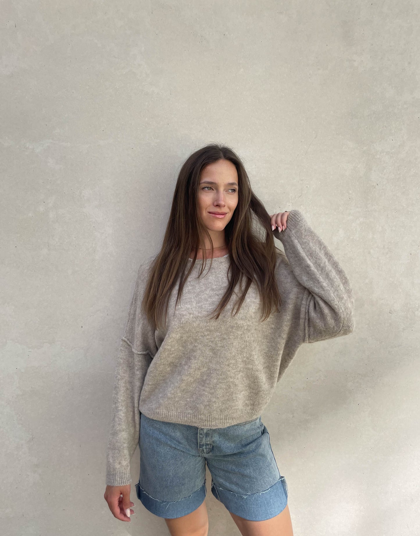 Frau mit brauen Haaren trägt Pullover mit Außennaht in Taupe 01