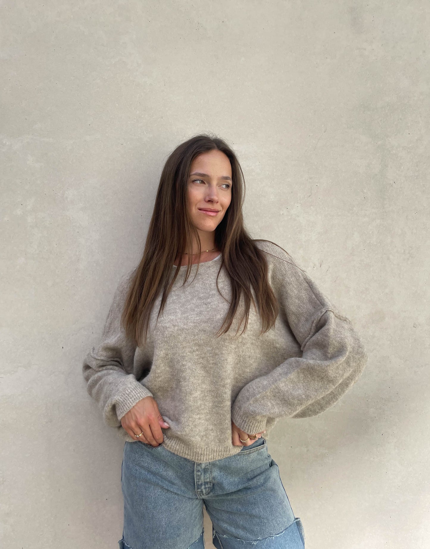 Frau mit brauen Haaren trägt Pullover mit Außennaht in Taupe 02