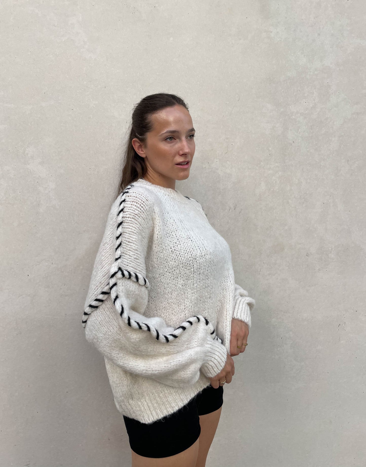 Frau mit brauen Haaren trägt Oversize Pullover in Wollweiß