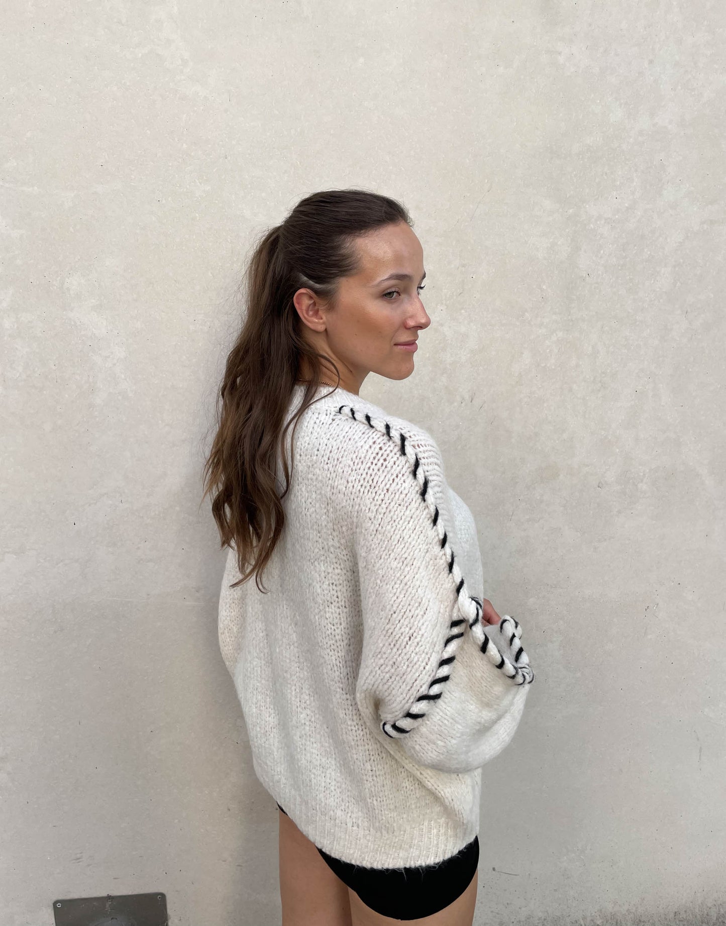 Frau mit brauen Haaren trägt Oversize Pullover in Wollweiß