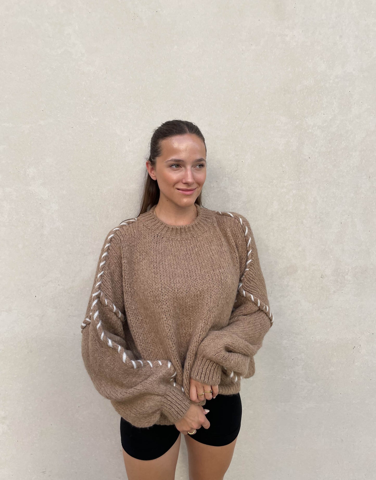 Frau mit brauen Haaren trägt Oversize Pullover in camel