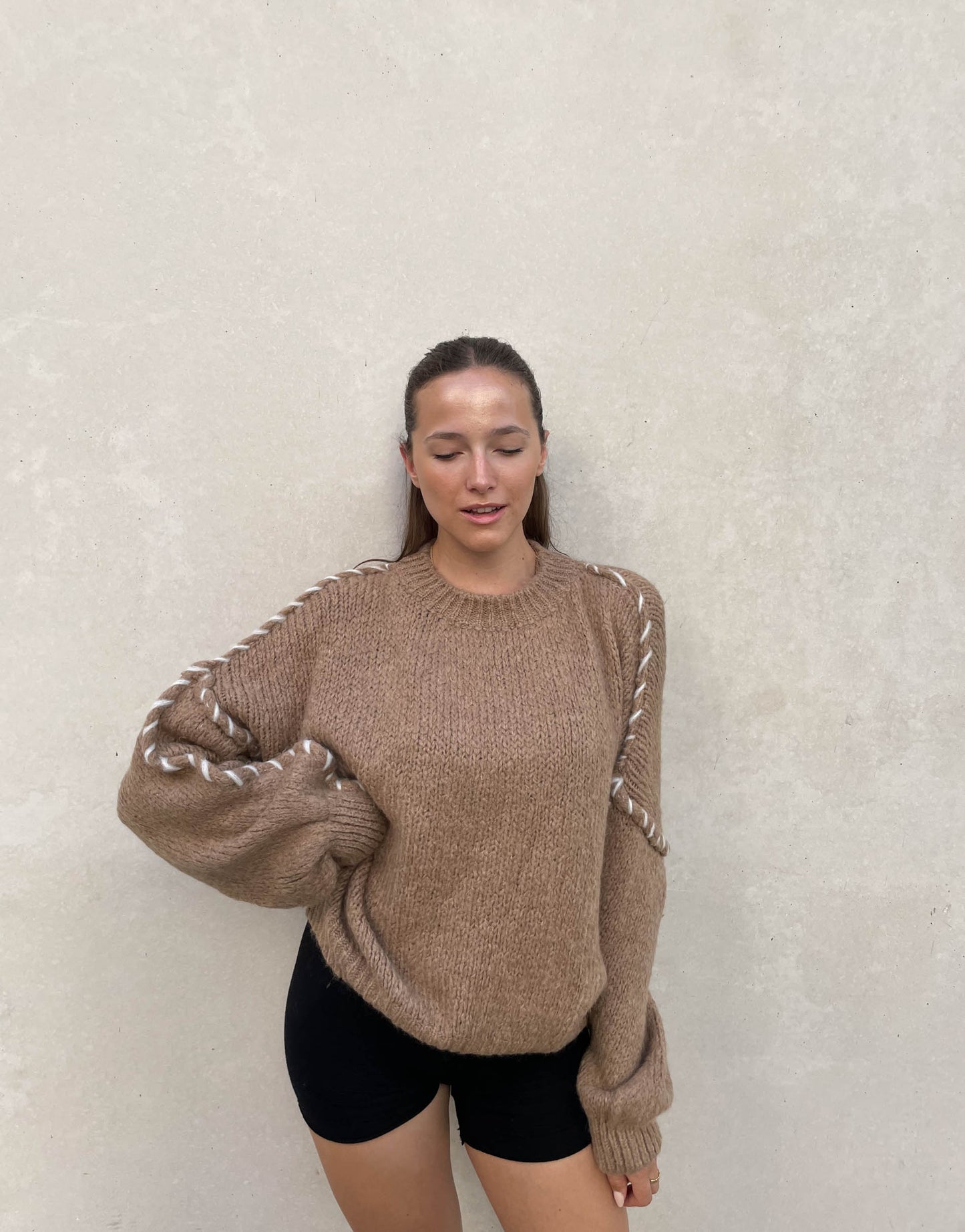 Frau mit brauen Haaren trägt Oversize Pullover in camel