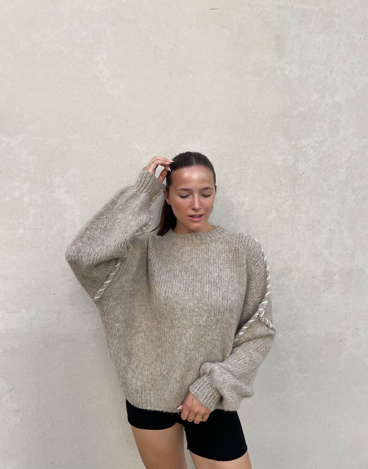 Frau mit brauen Haaren trägt Oversize Pullover in Beige