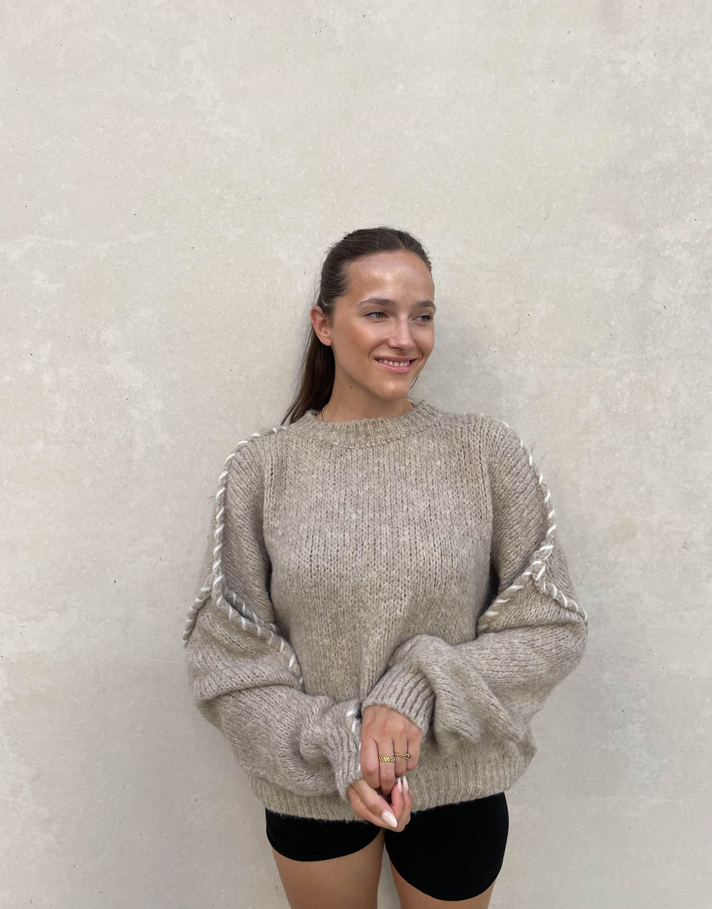 Frau mit brauen Haaren trägt Oversize Pullover in Beige
