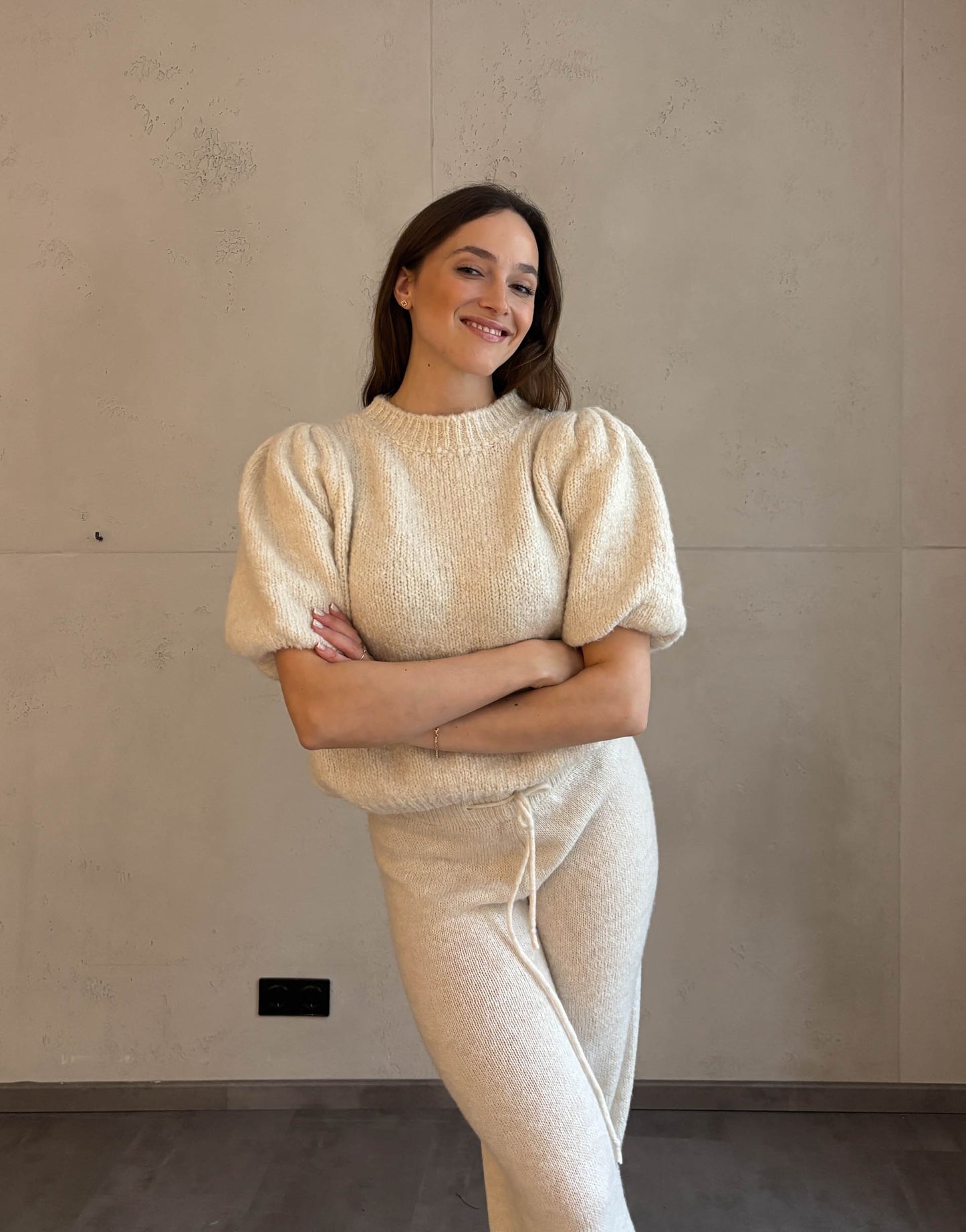 Frau mit braunen Haaren trägt Pullover mit Puffärmeln in Beige