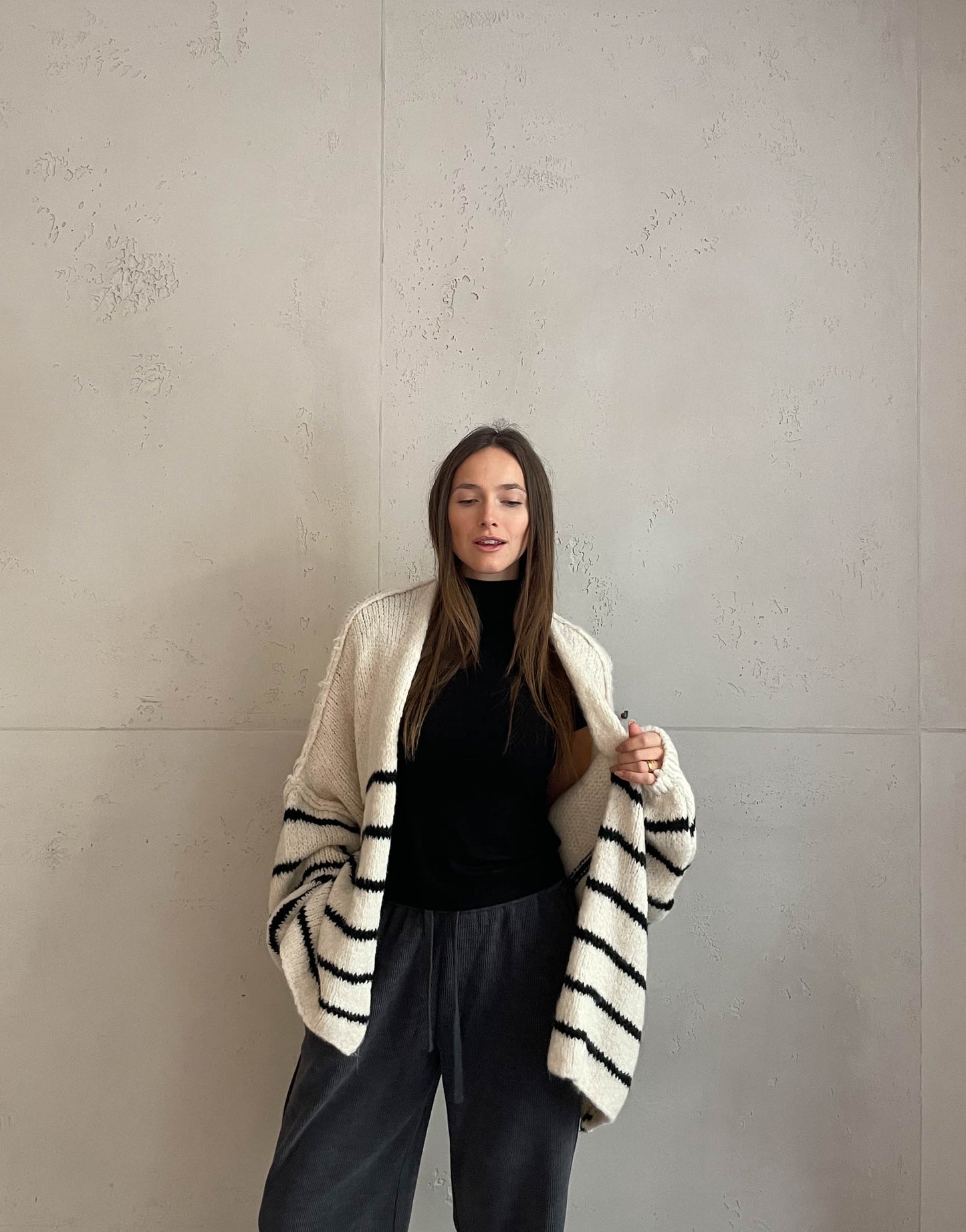 Frau mit brauen Haaren trägt oversize Cardigan mit Streifen in beige