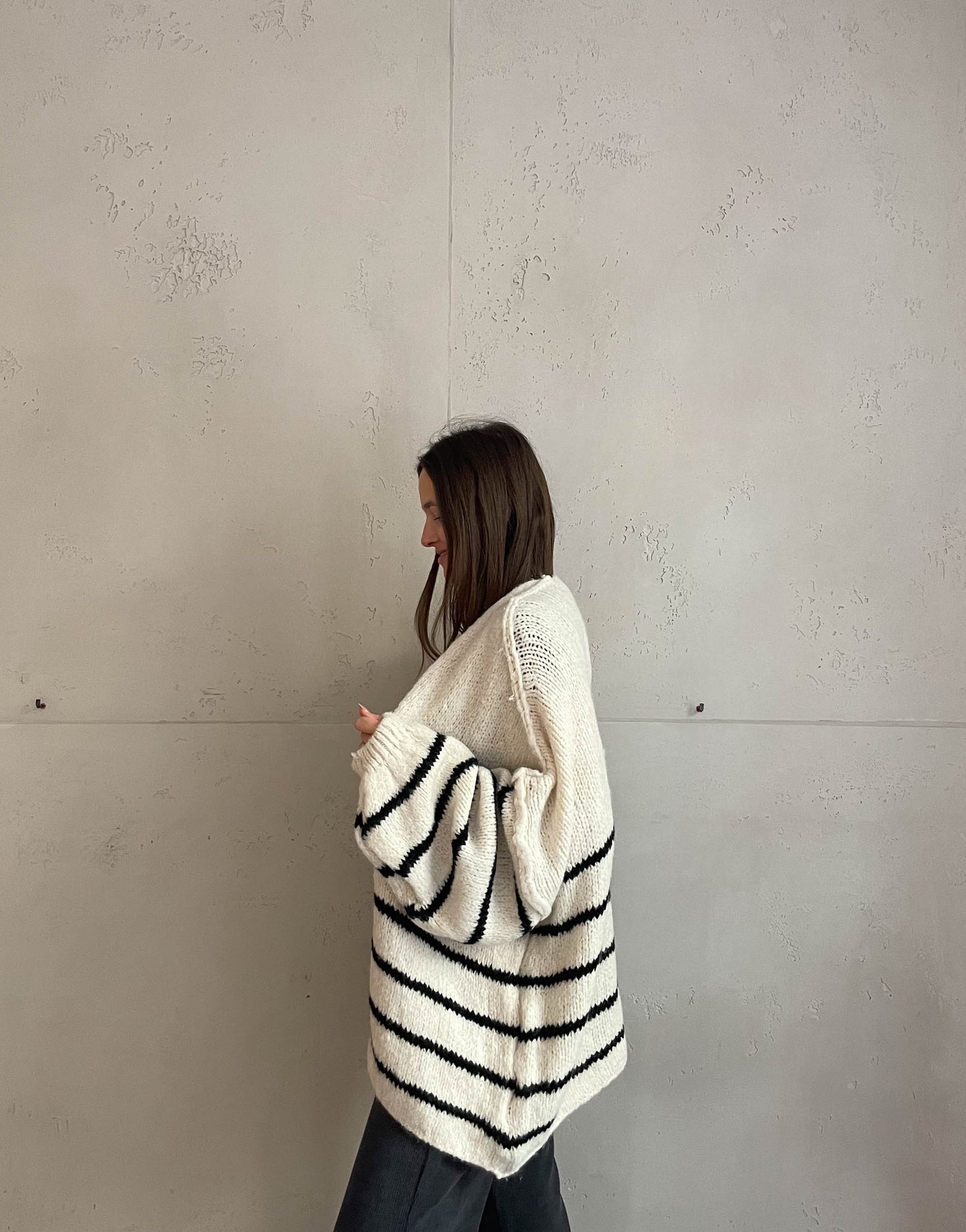Frau mit brauen Haaren trägt oversize Cardigan mit Streifen in beige