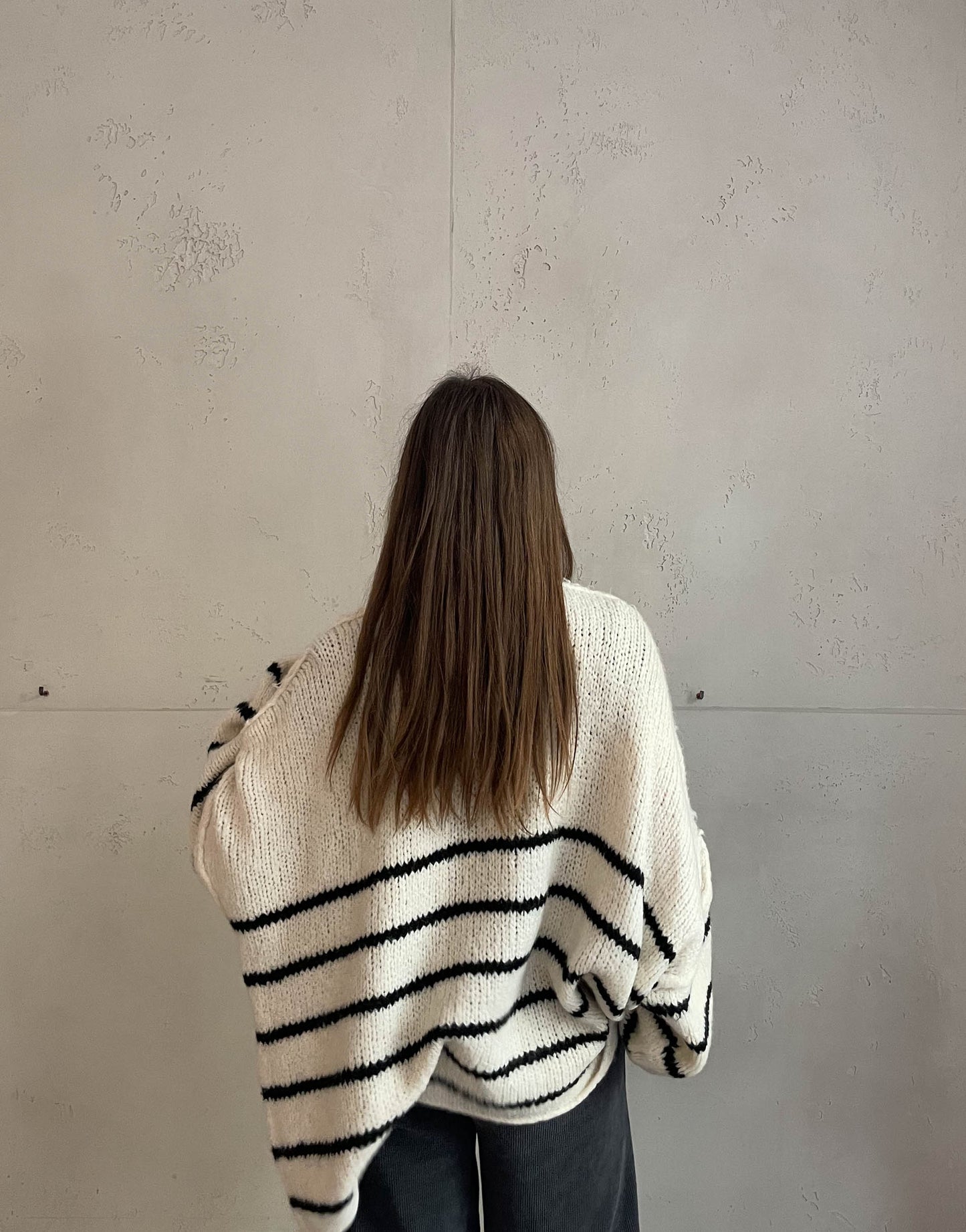 Frau mit brauen Haaren trägt oversize Cardigan mit Streifen in beige