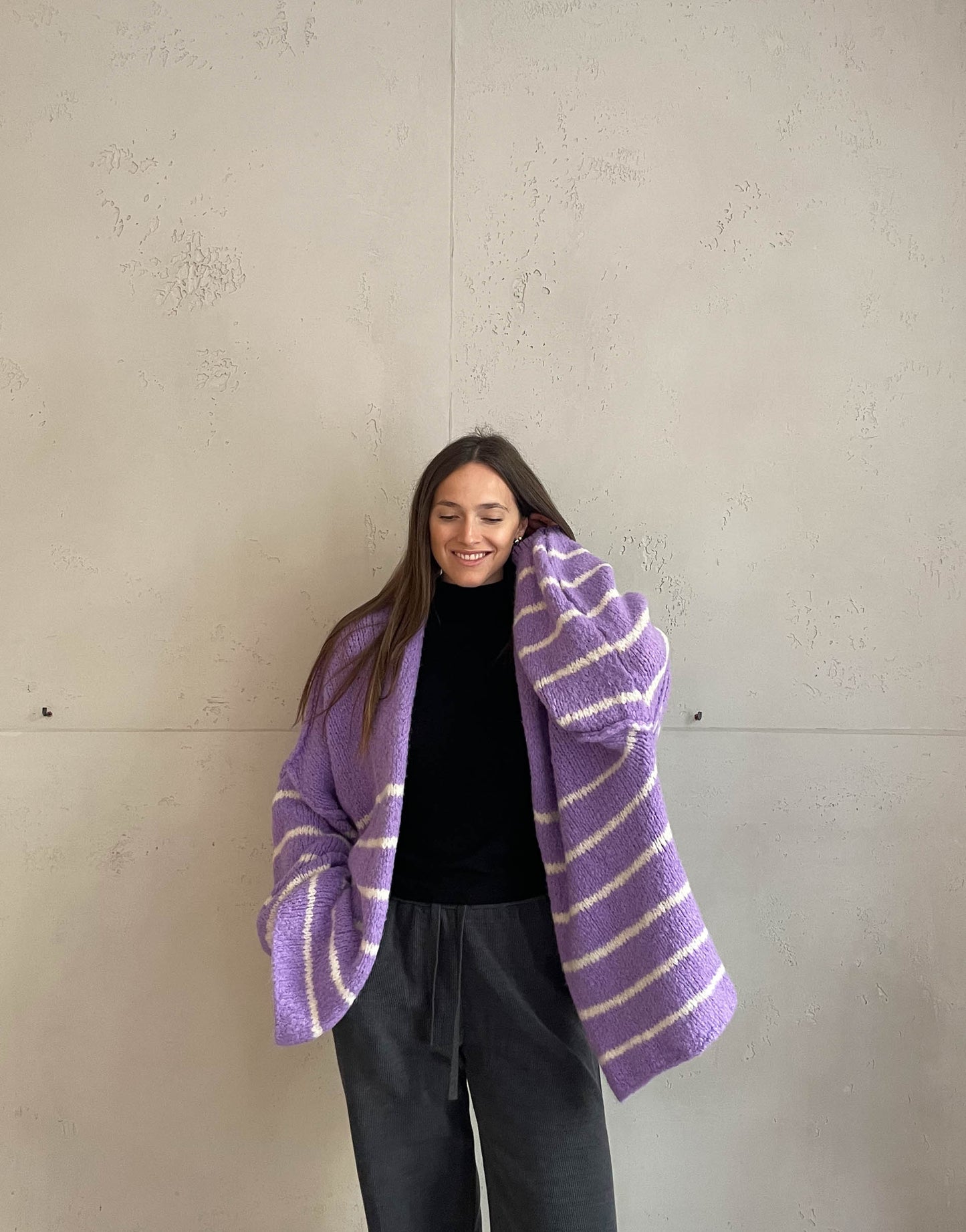 Frau mit brauen Haaren trägt oversize Cardigan mit Streifen in lila
