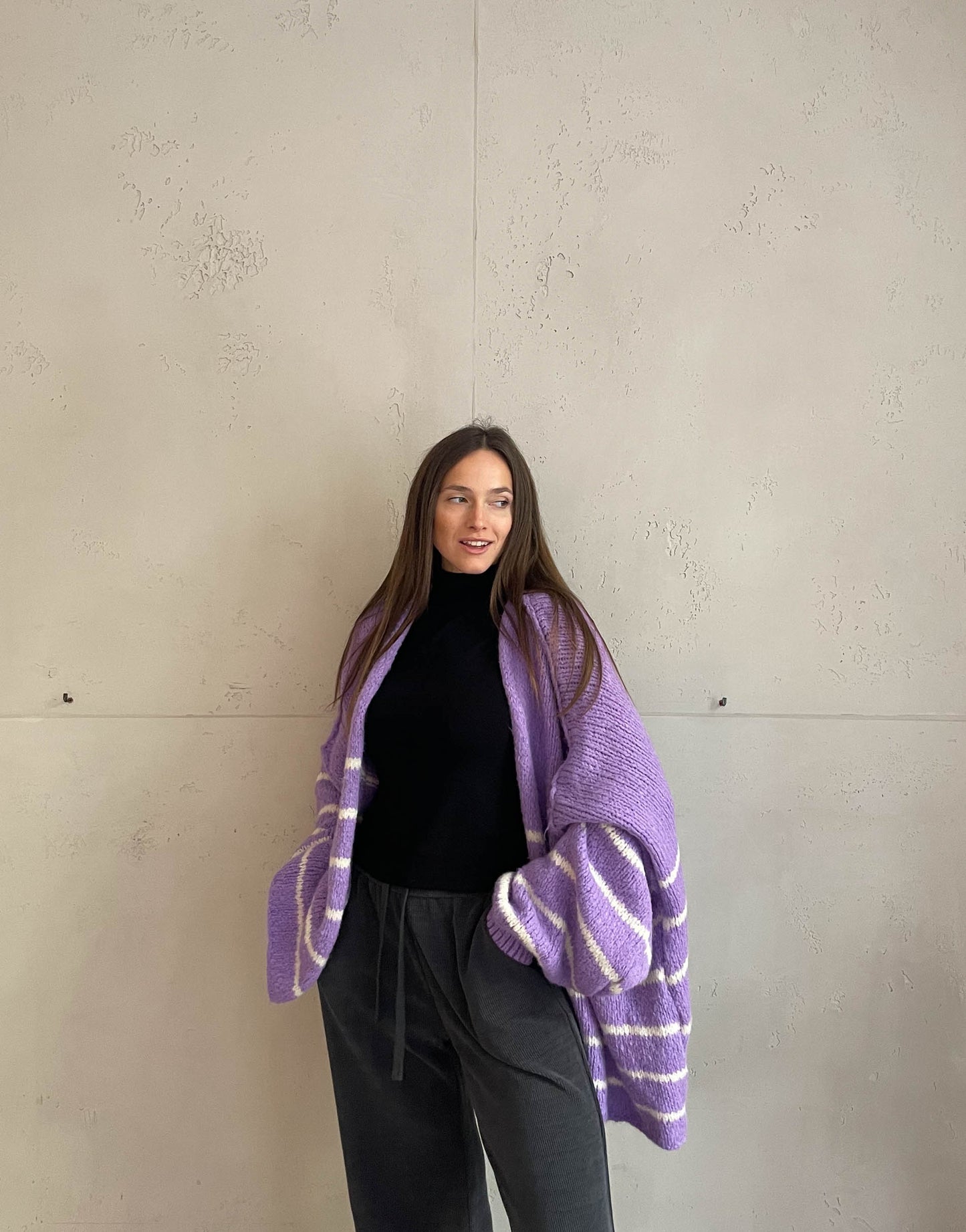 Frau mit brauen Haaren trägt oversize Cardigan mit Streifen in lila