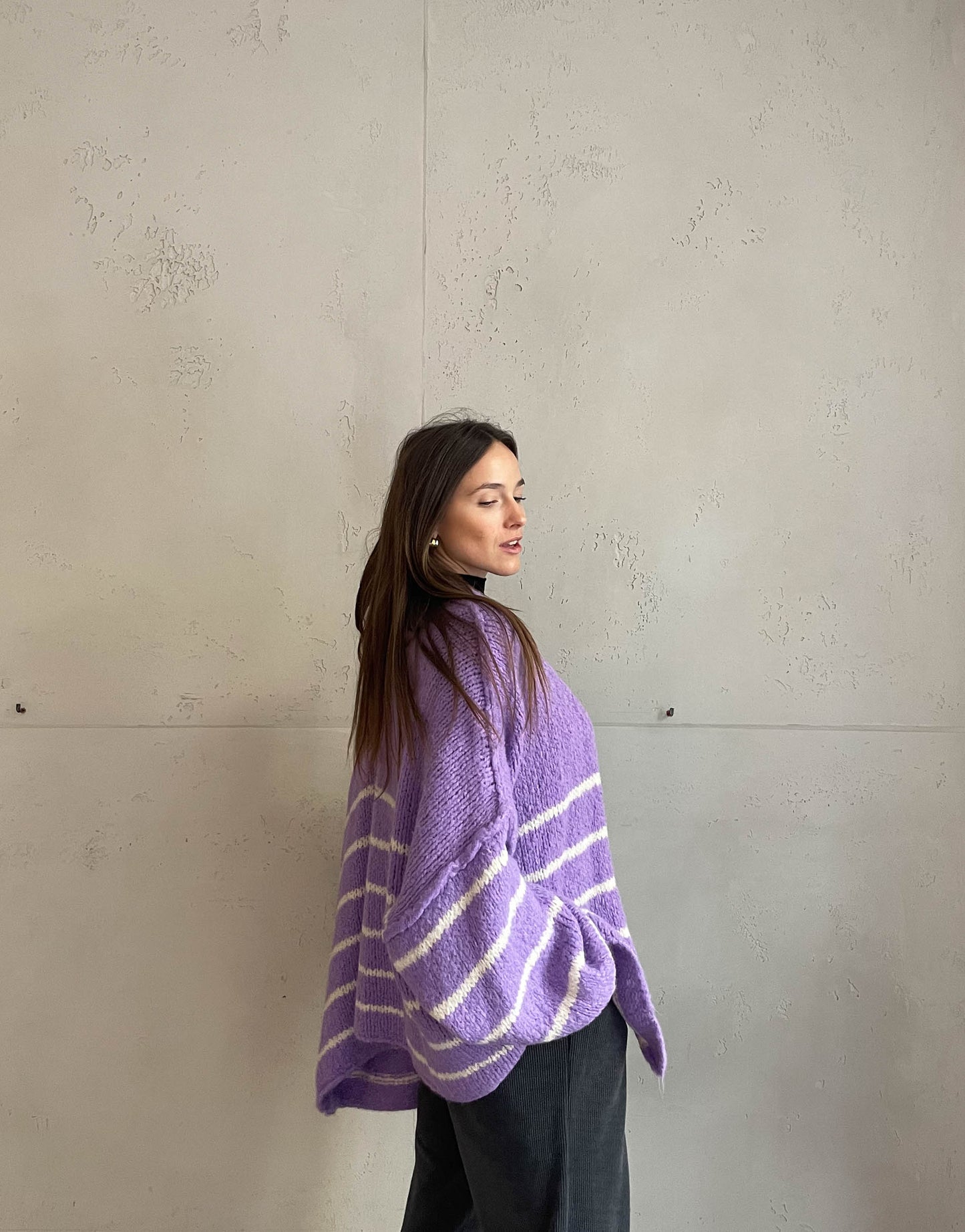 Frau mit brauen Haaren trägt oversize Cardigan mit Streifen in lila