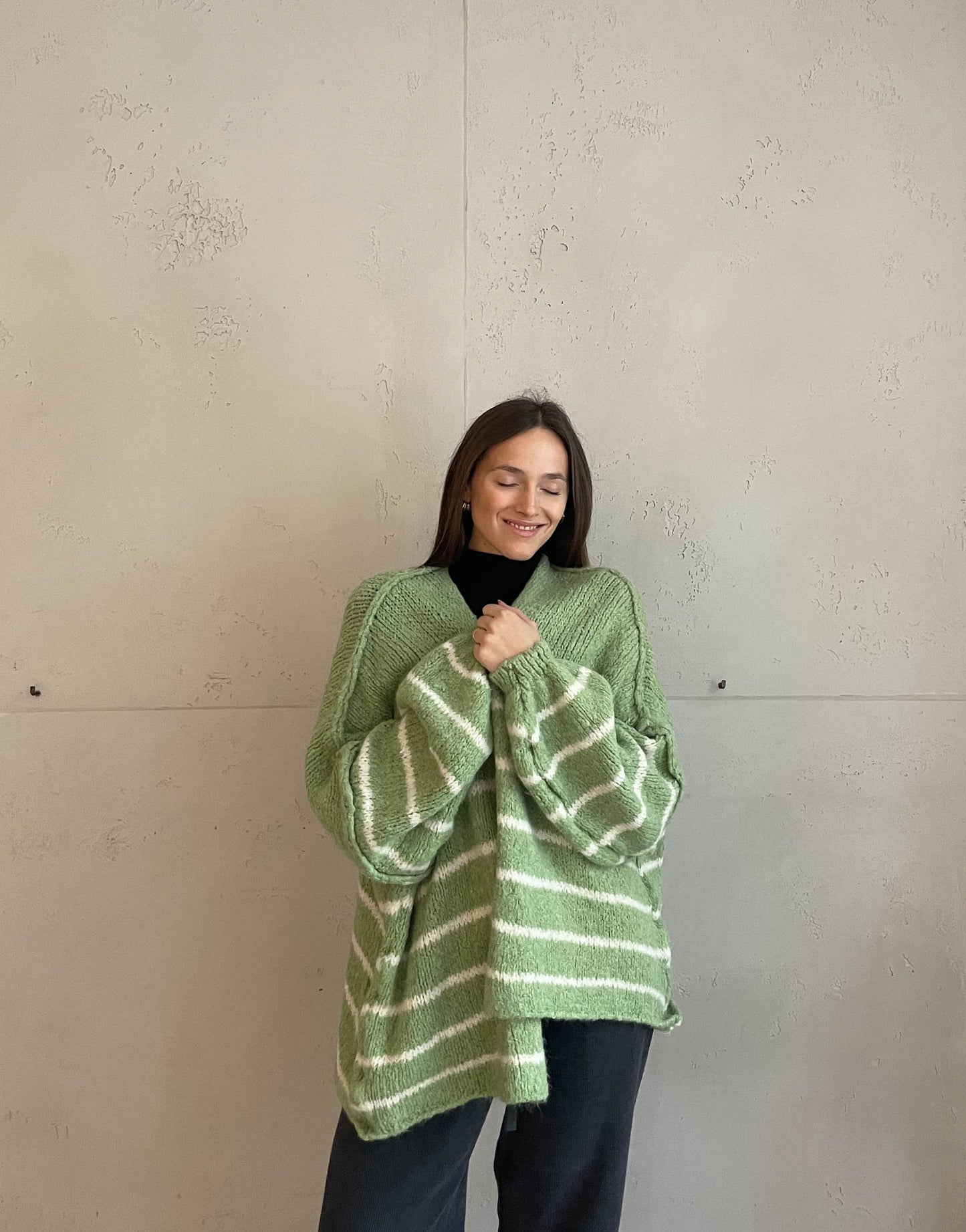 Frau mit brauen Haaren trägt oversize Cardigan mit Streifen in mint