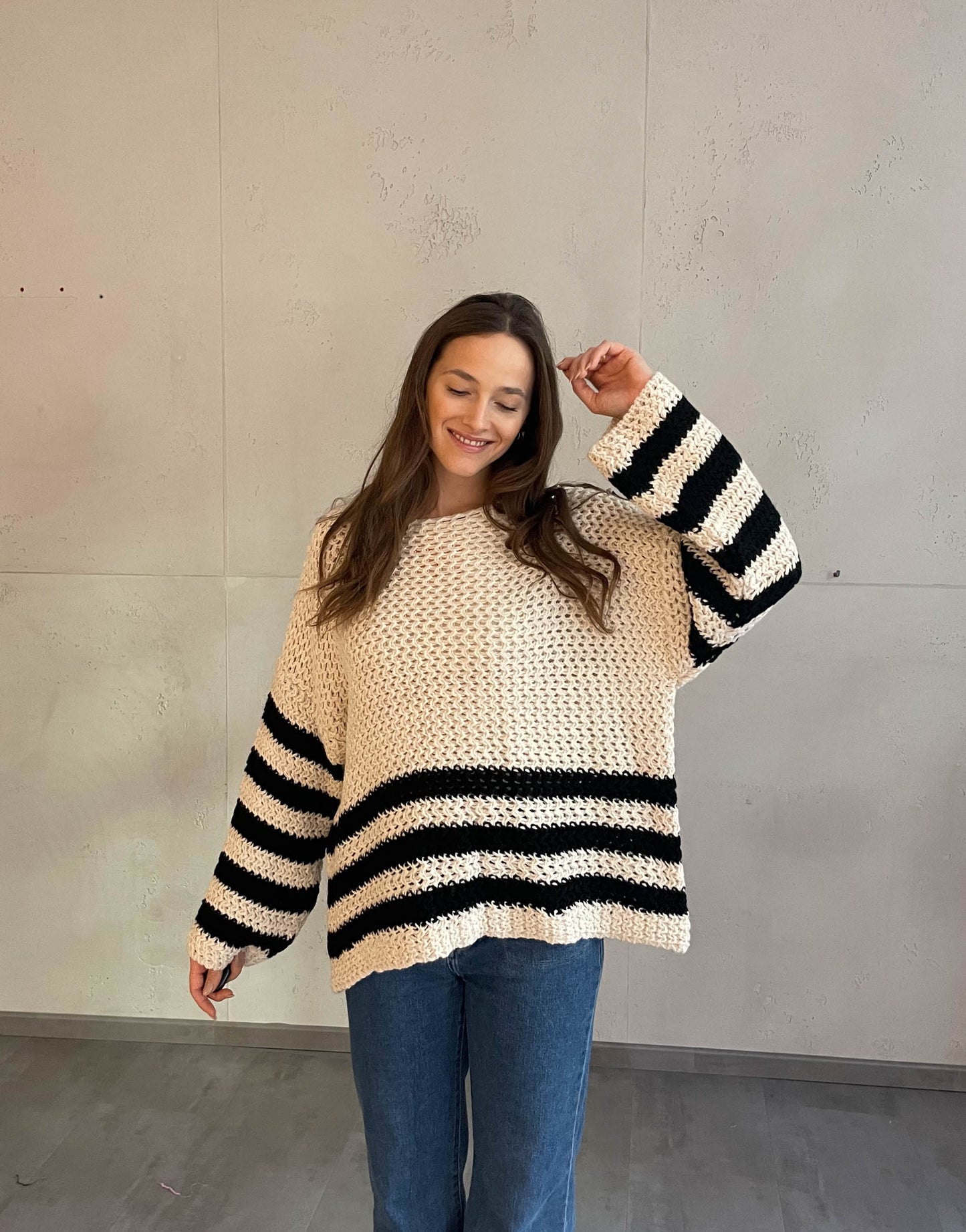 Frau mit brauen Haaren trägt Streifenpullover in beige