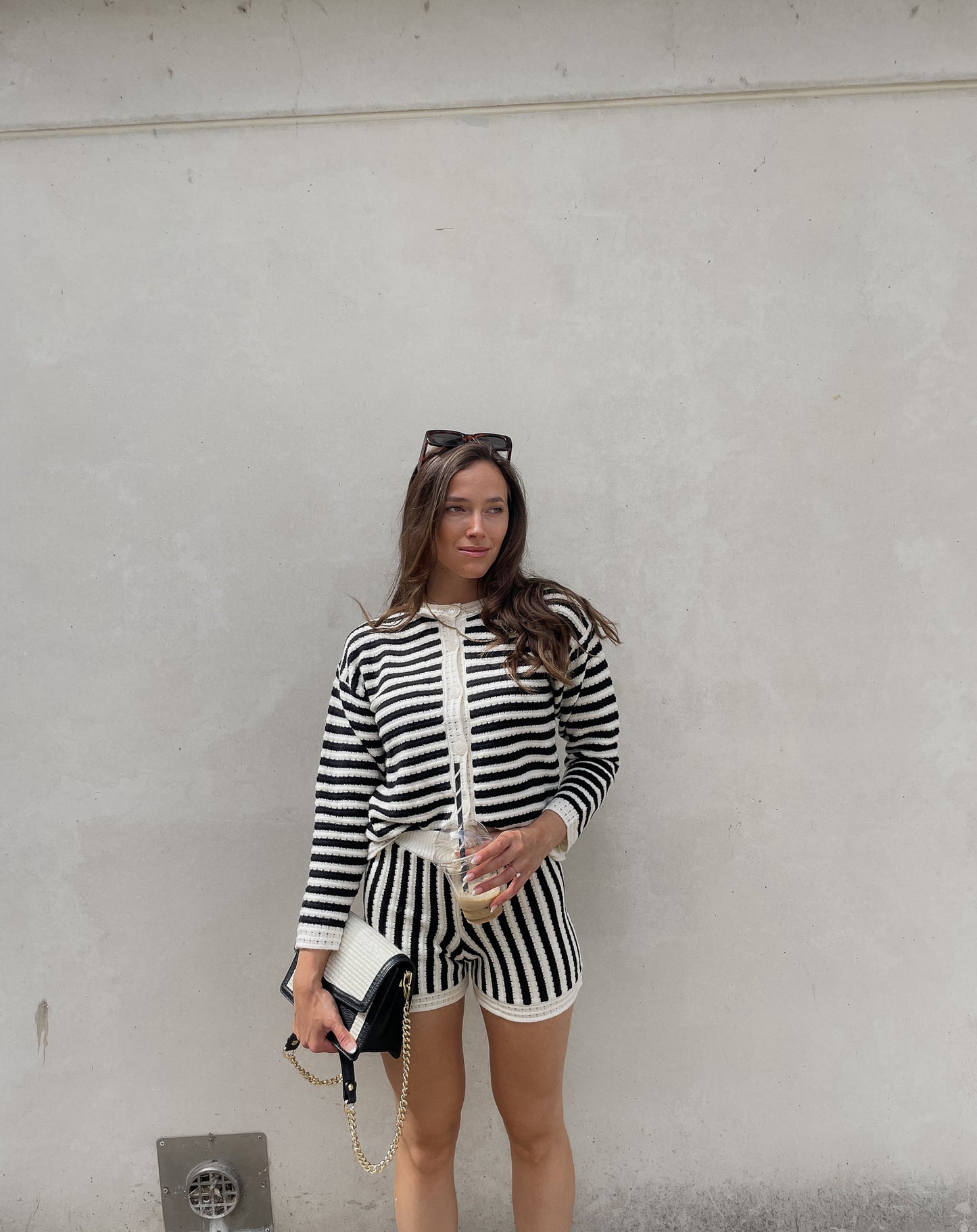 Frau mit brauen Haaren trägt Streifenset bestehend aus Shorts und kurzer Strickjacke