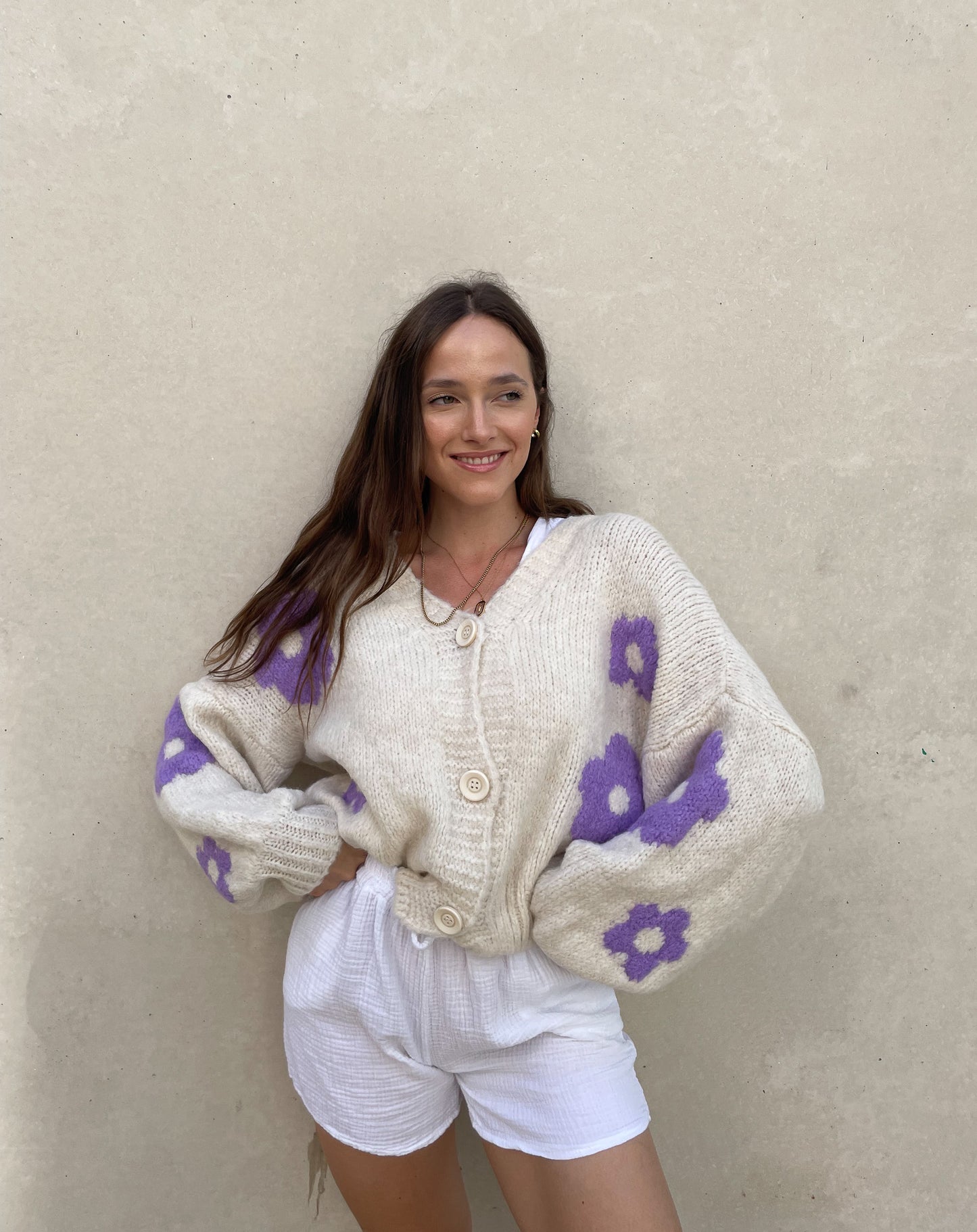 Frau mit brauen Haaren trägt Strickjacke mit Blumenprint