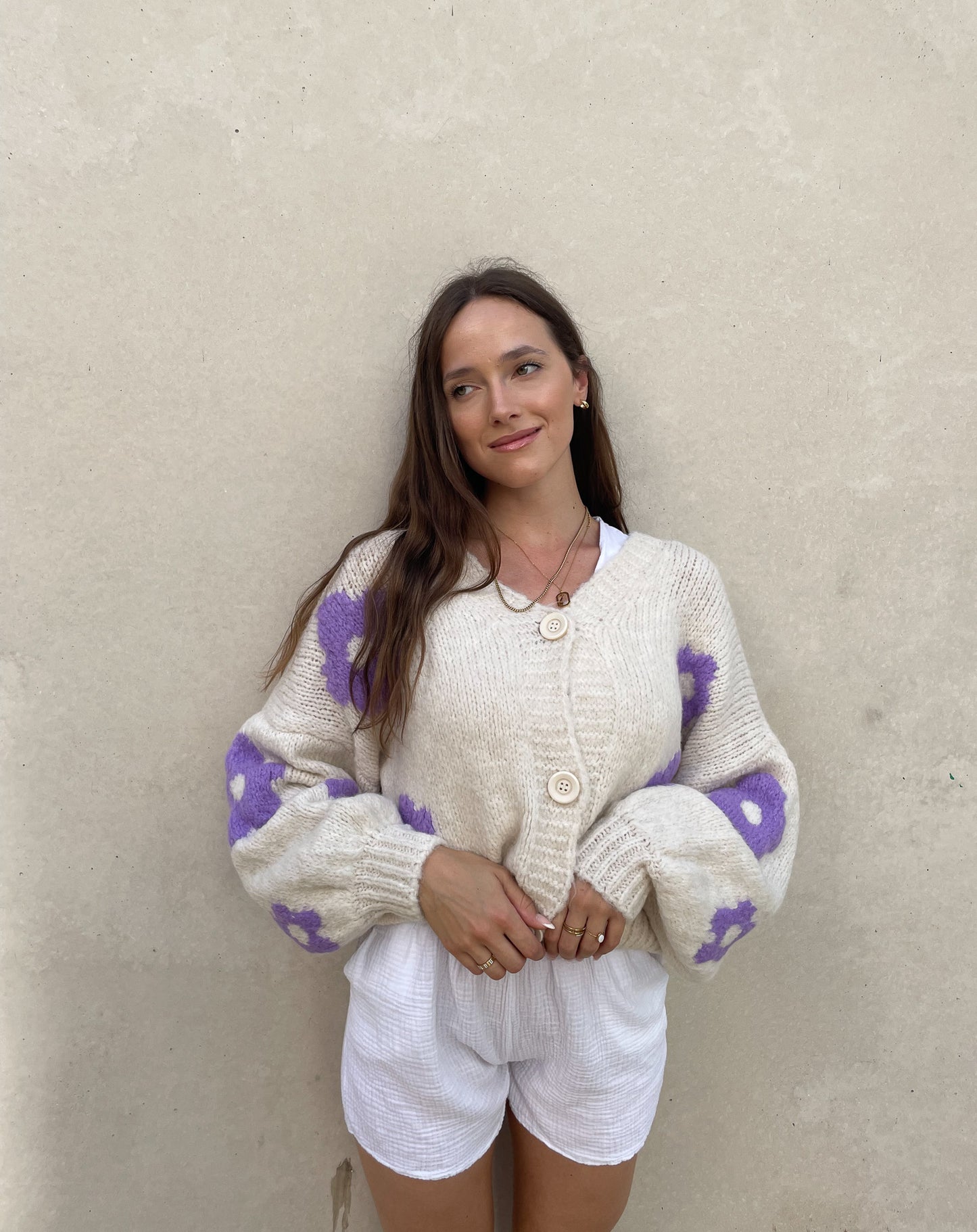 Frau mit brauen Haaren trägt Strickjacke mit Blumenprint