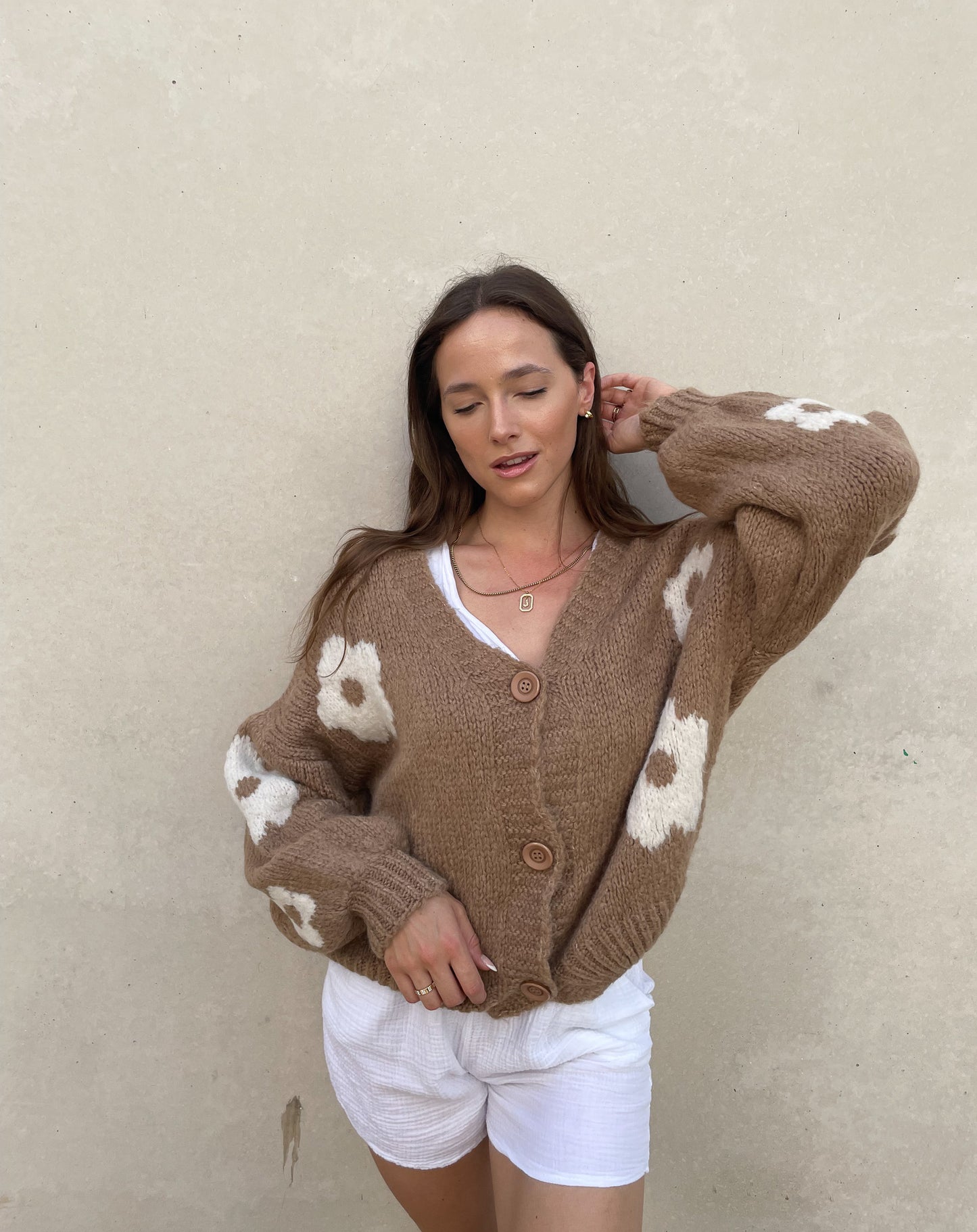 Frau mit brauen Haaren trägt Strickjacke mit Blumenprint