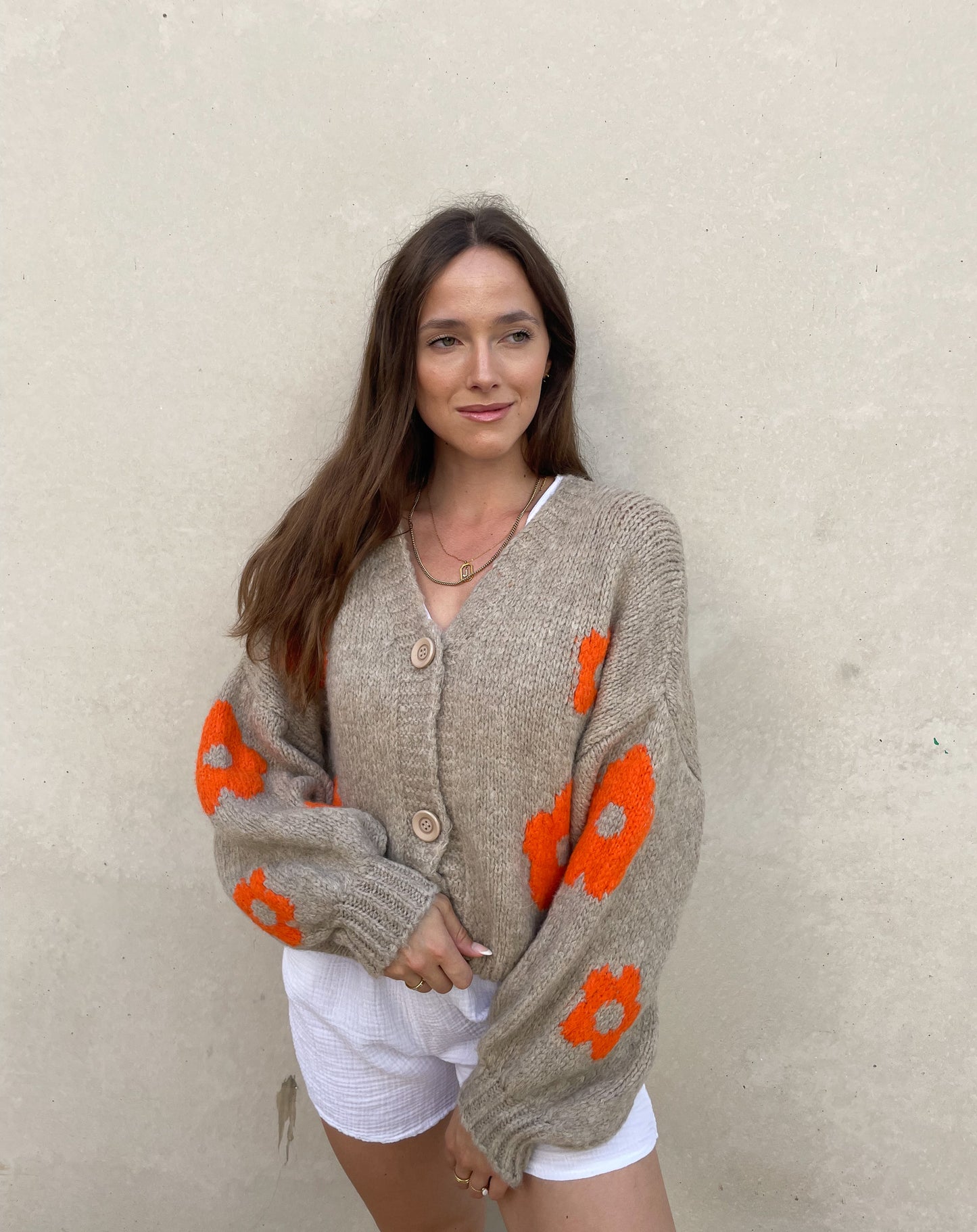 Frau mit brauen Haaren trägt Strickjacke mit Blumenprint