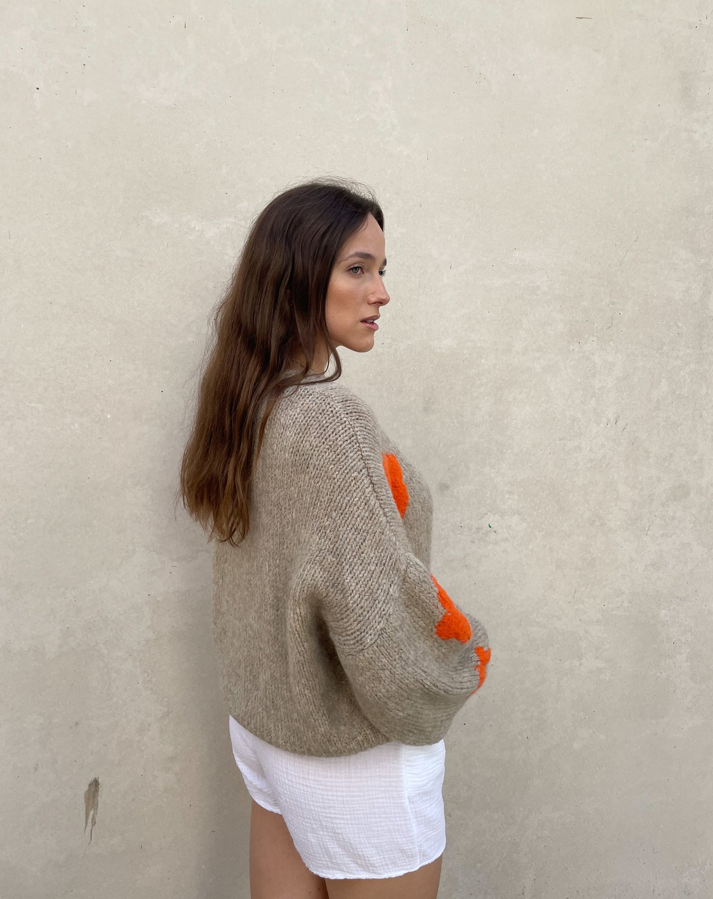 Frau mit brauen Haaren trägt Strickjacke mit Blumenprint