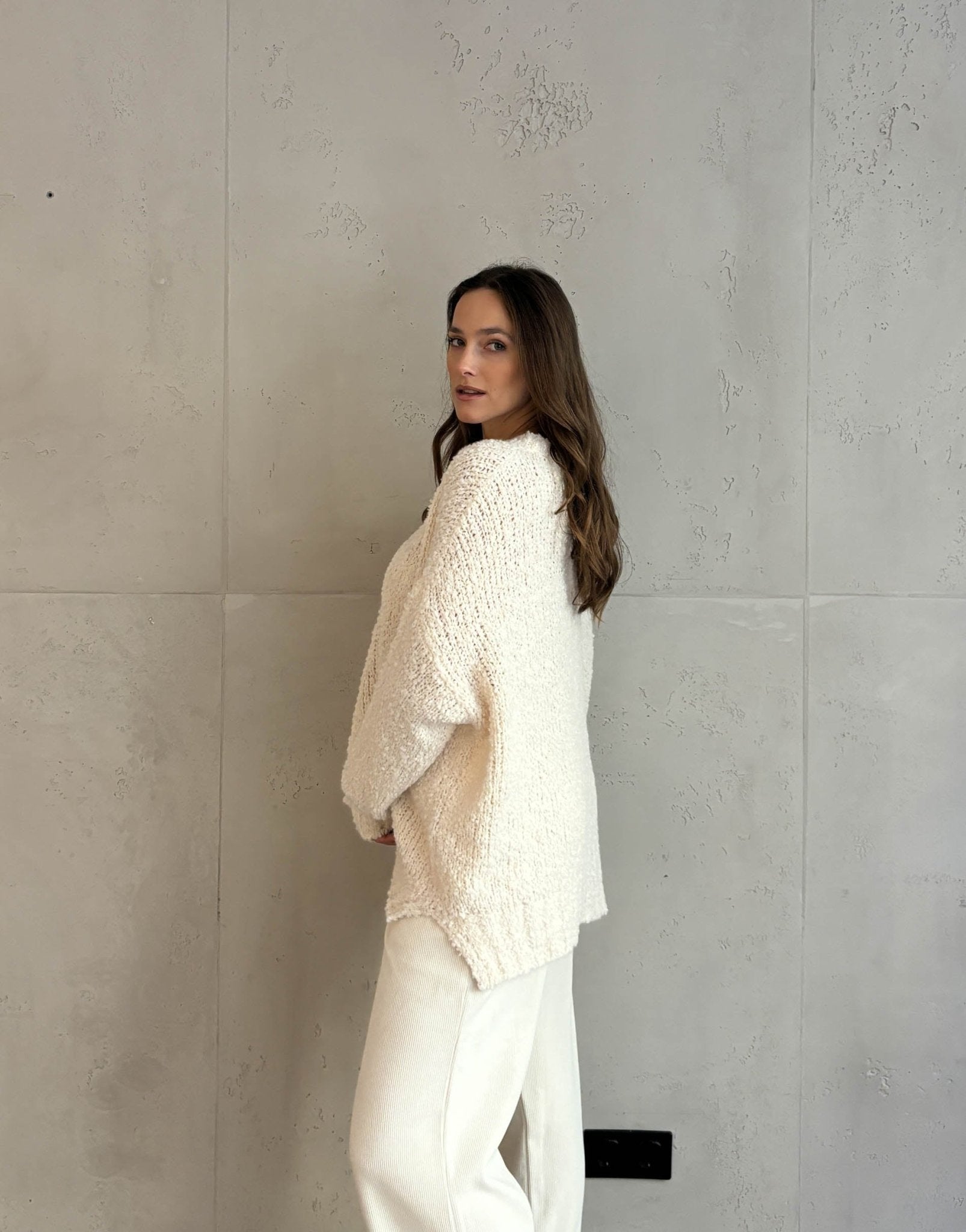 Frau mit braunen Haaren trägt oversize Boucle Pullover in beige