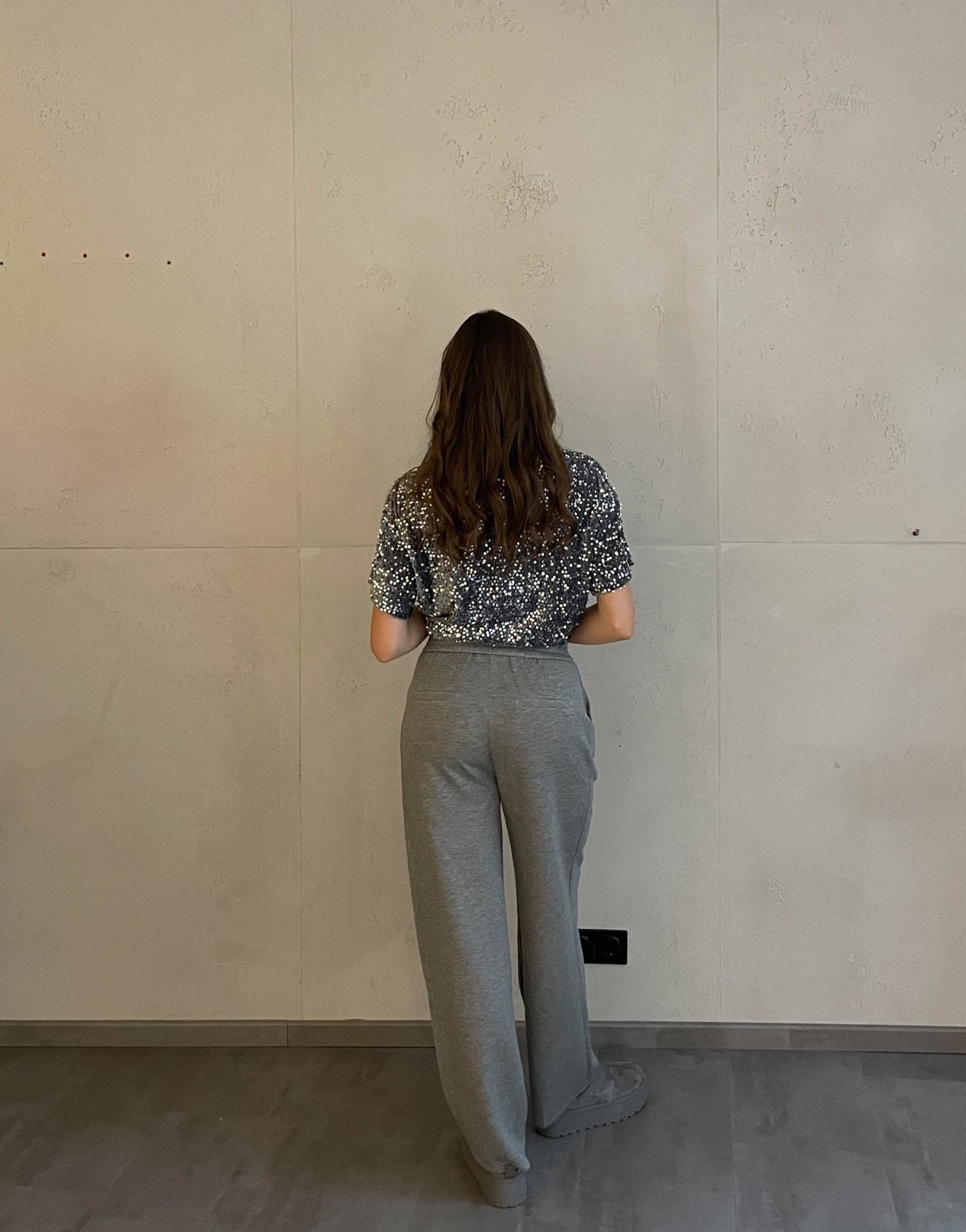 Frau mit braunen Haaren trägt Anzughose in Grau