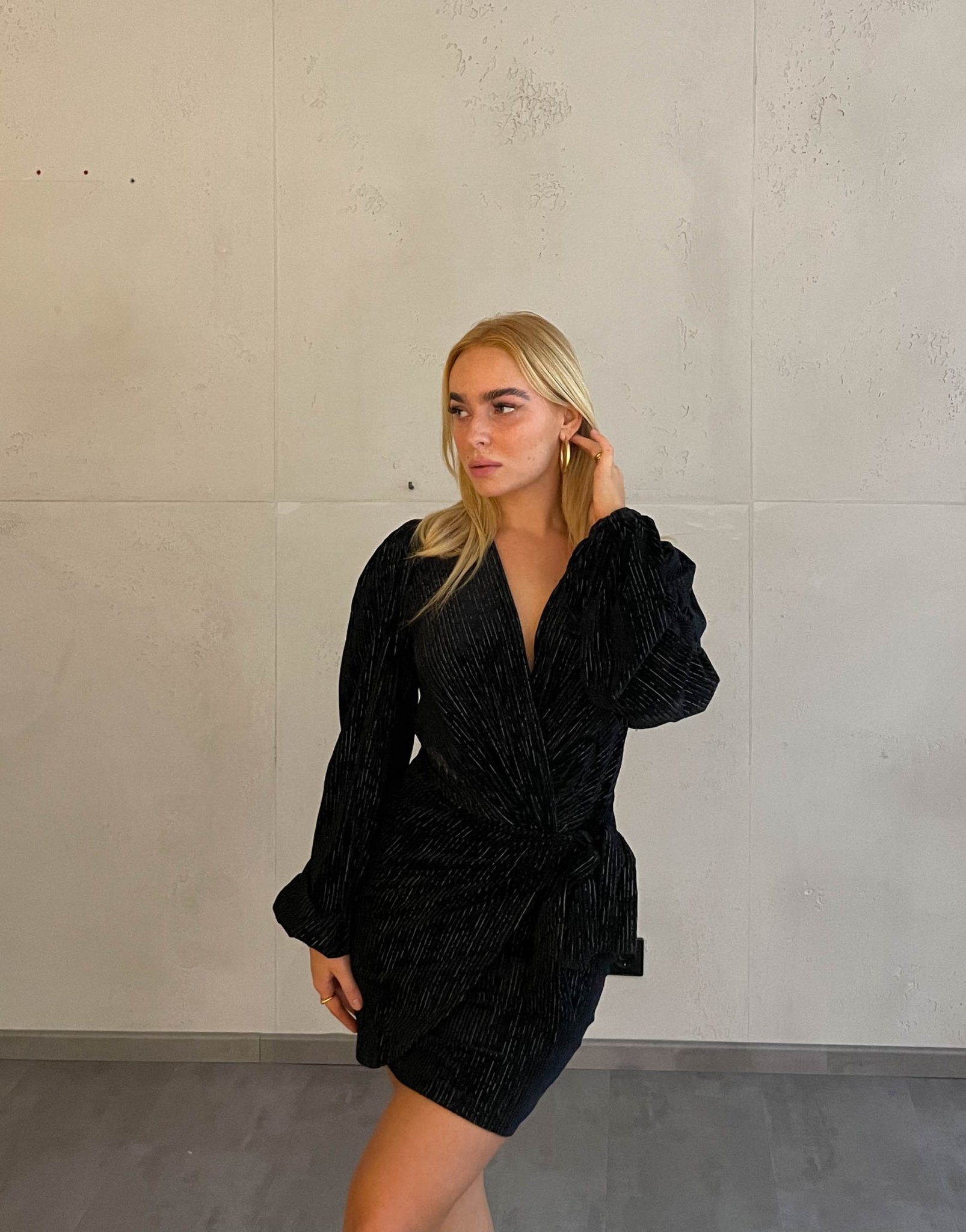 Frau mit blonden Haaren trägt mini Samtkleid in schwarz