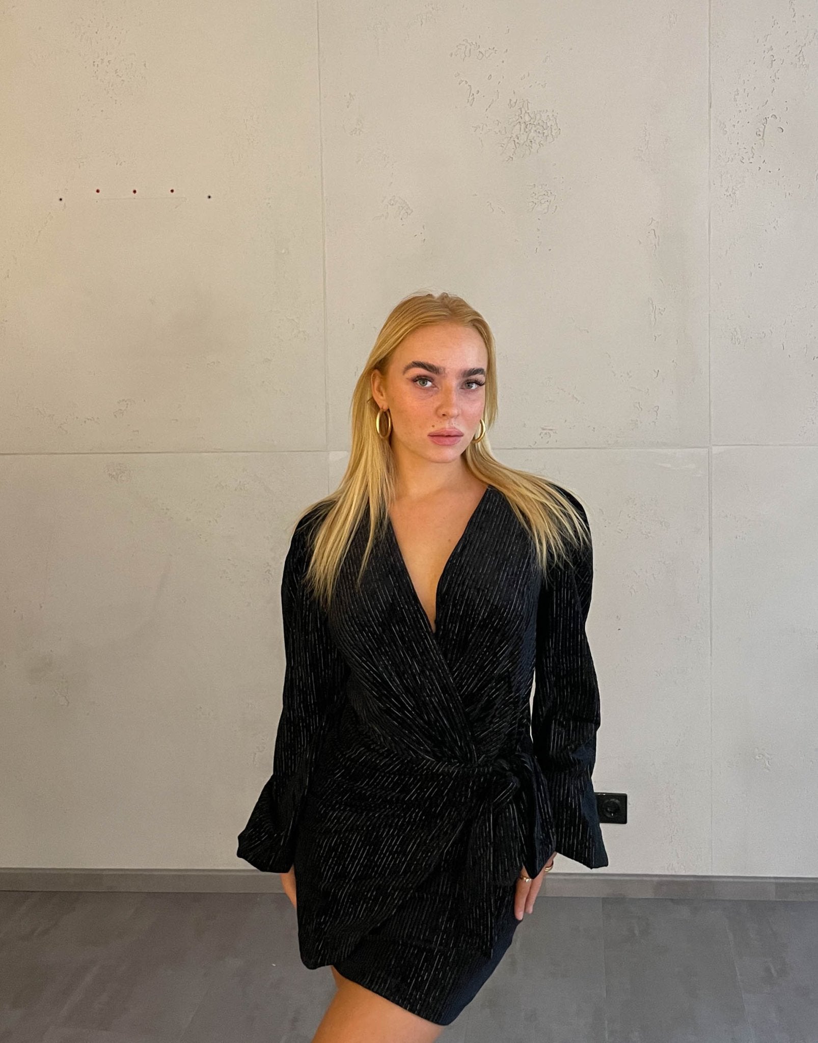 Frau mit blonden Haaren trägt mini Samtkleid in schwarz