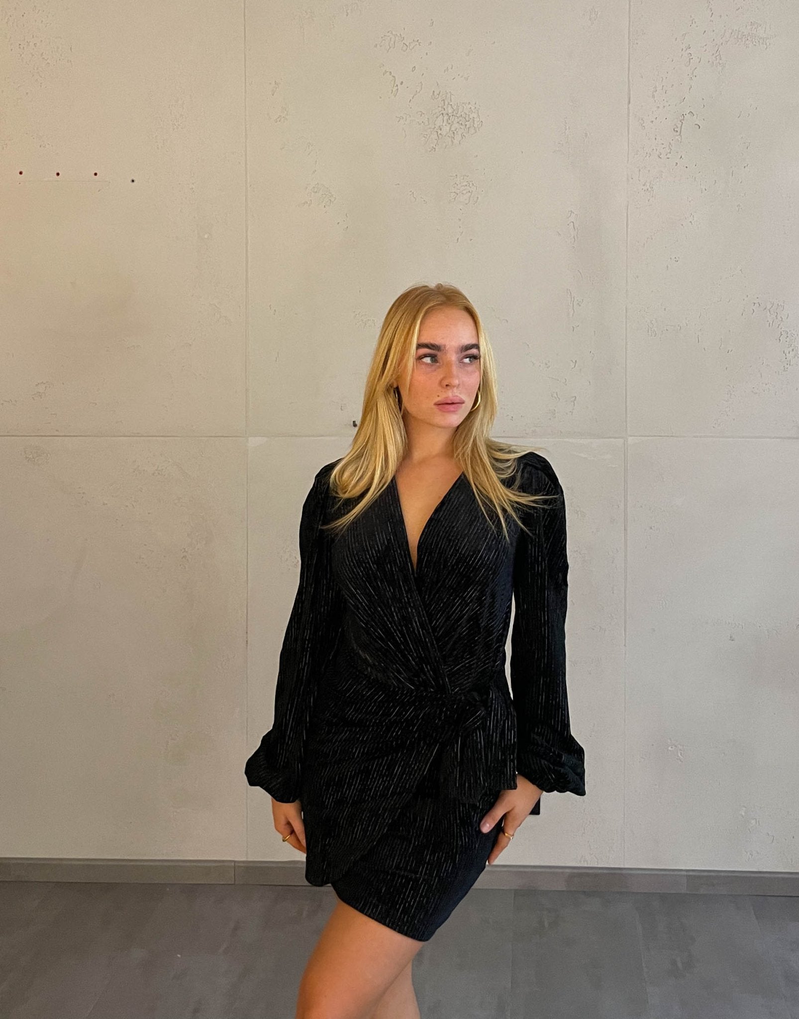 Frau mit blonden Haaren trägt mini Samtkleid in schwarz