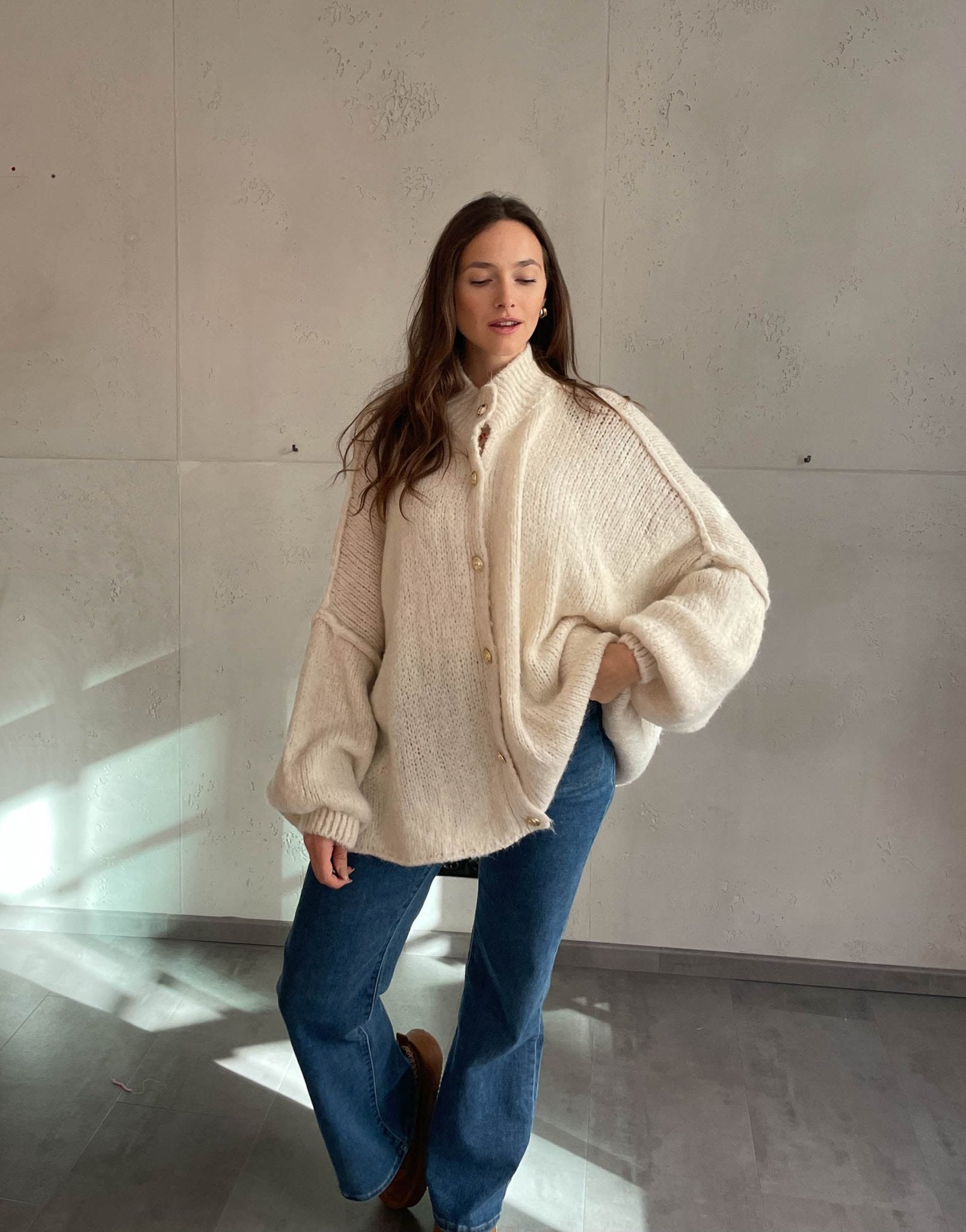 Frau mit brauen Haaren trägt oversize Strickjacke in Hellbeige