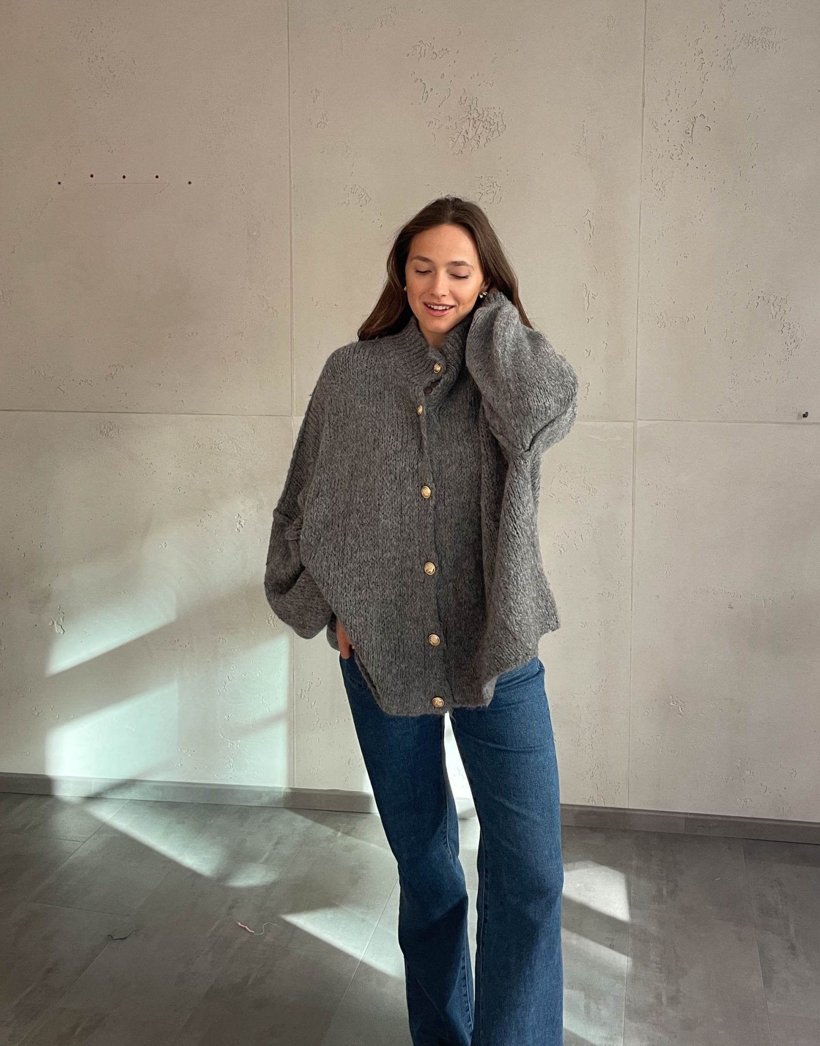 Frau mit brauen Haaren trägt oversize Strickjacke in Dunklegrau