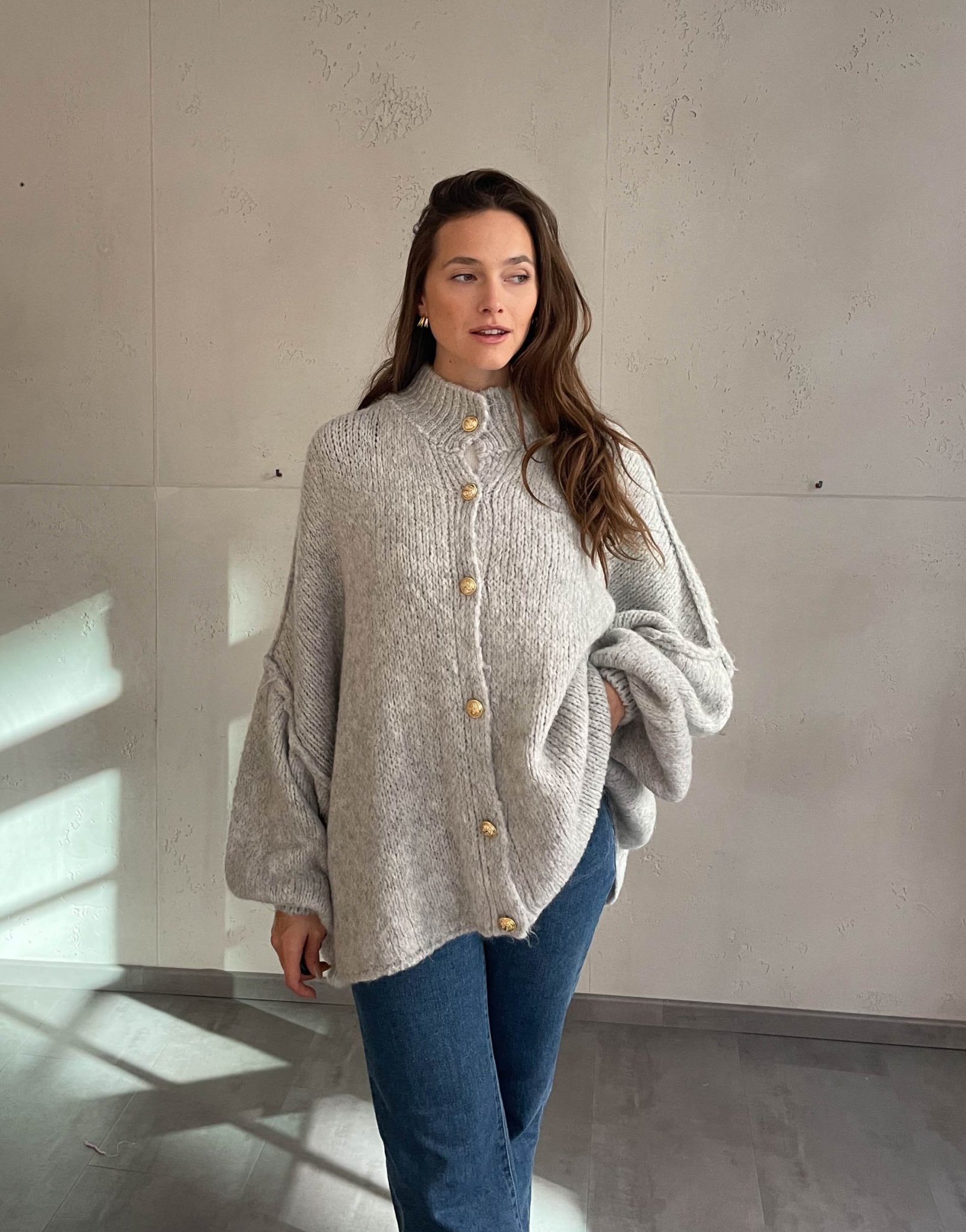 Frau mit brauen Haaren trägt oversize Strickjacke in Hellgrau