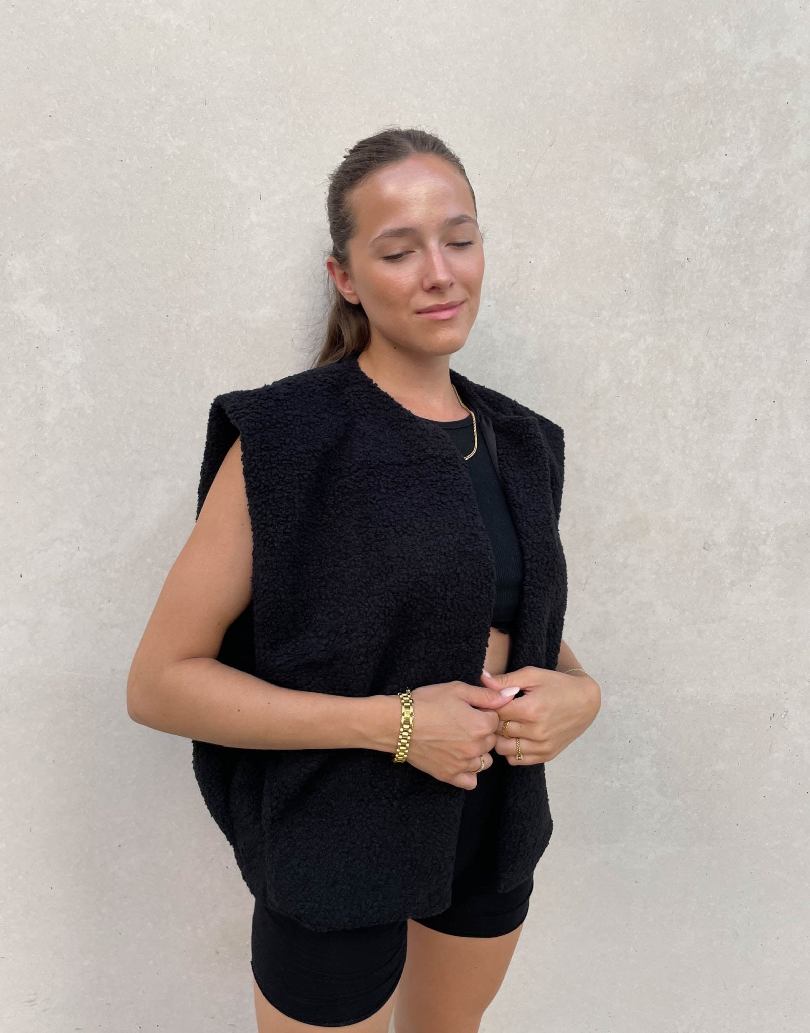 Frau mit brauen Haaren trägt Teddy Weste in Schwarz