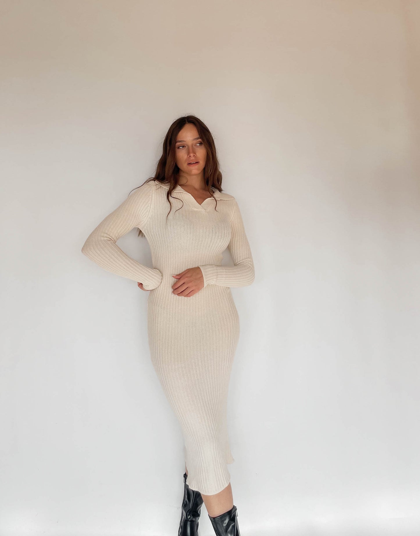 Frau mit brauen Haaren trägt Strickkleid in Beige