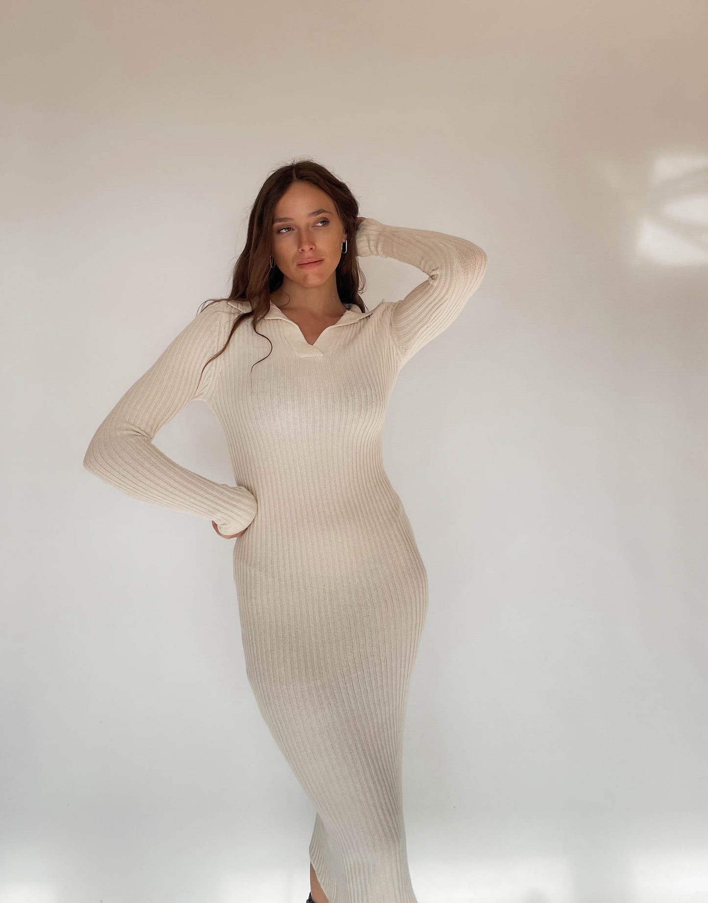 Frau mit brauen Haaren trägt Strickkleid in Beige