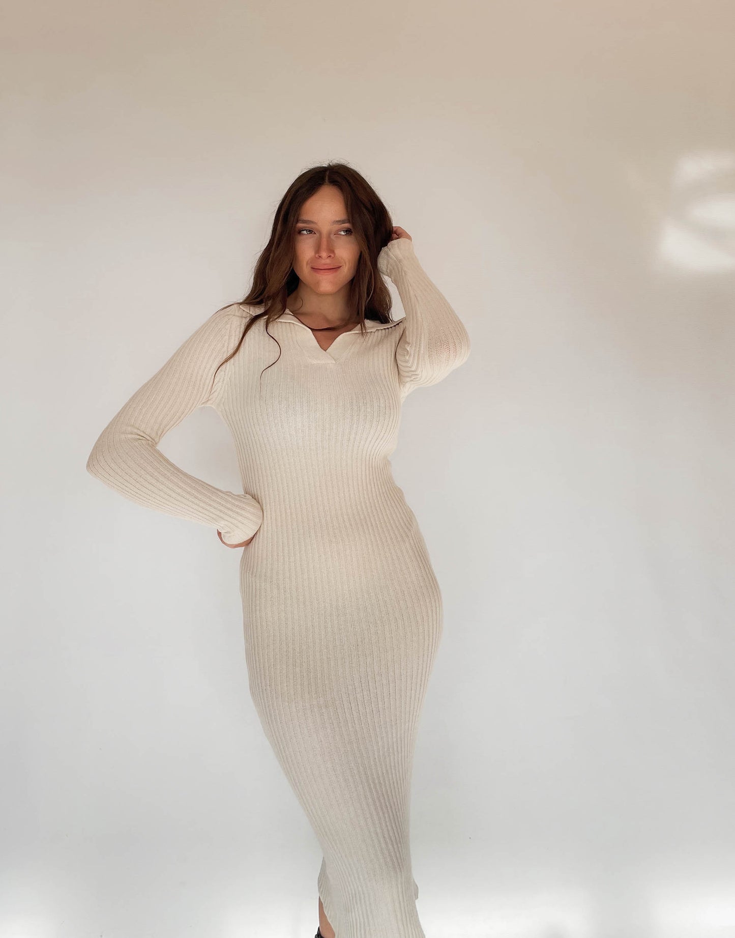 Frau mit brauen Haaren trägt Strickkleid in Beige