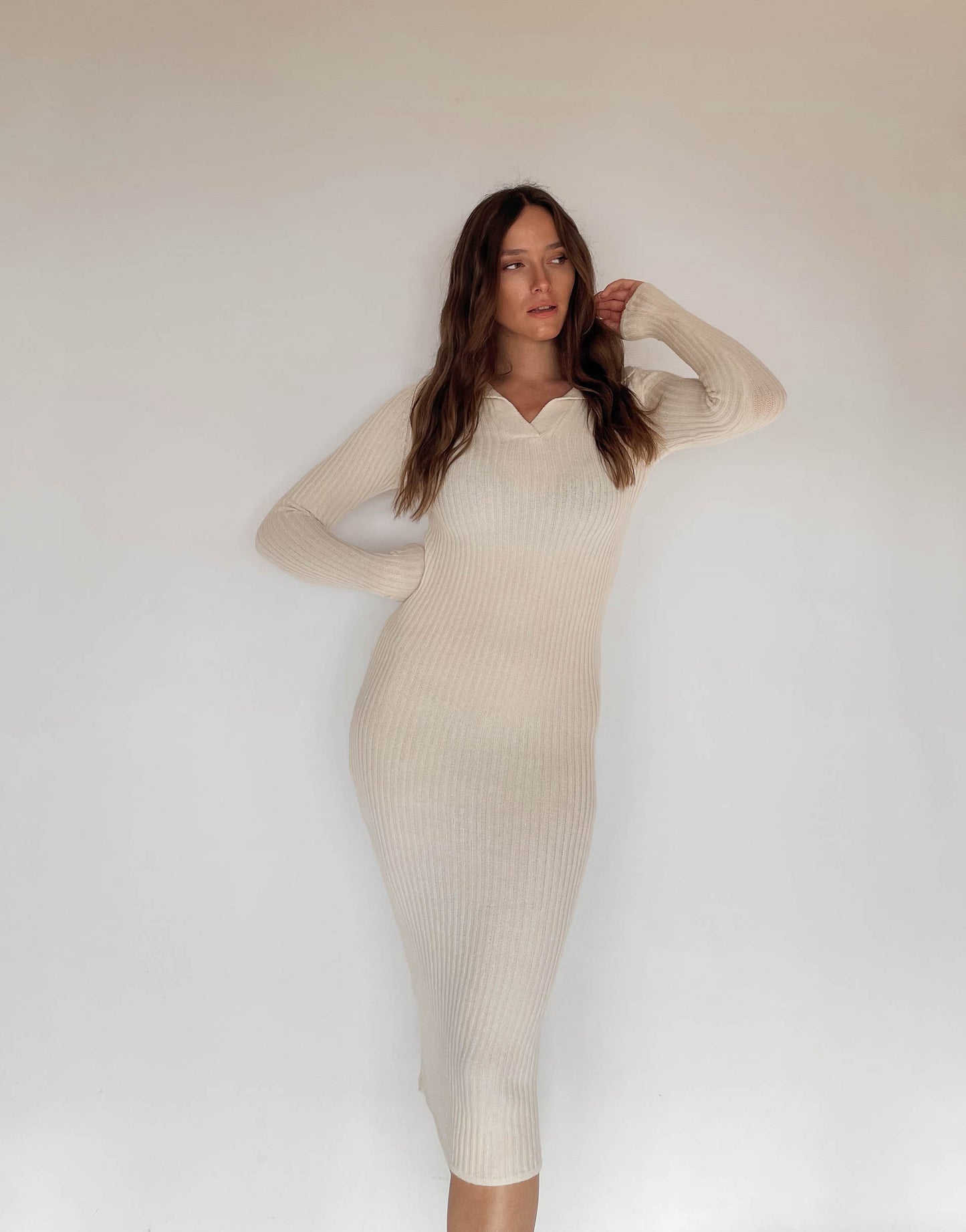 Frau mit brauen Haaren trägt Strickkleid in Beige