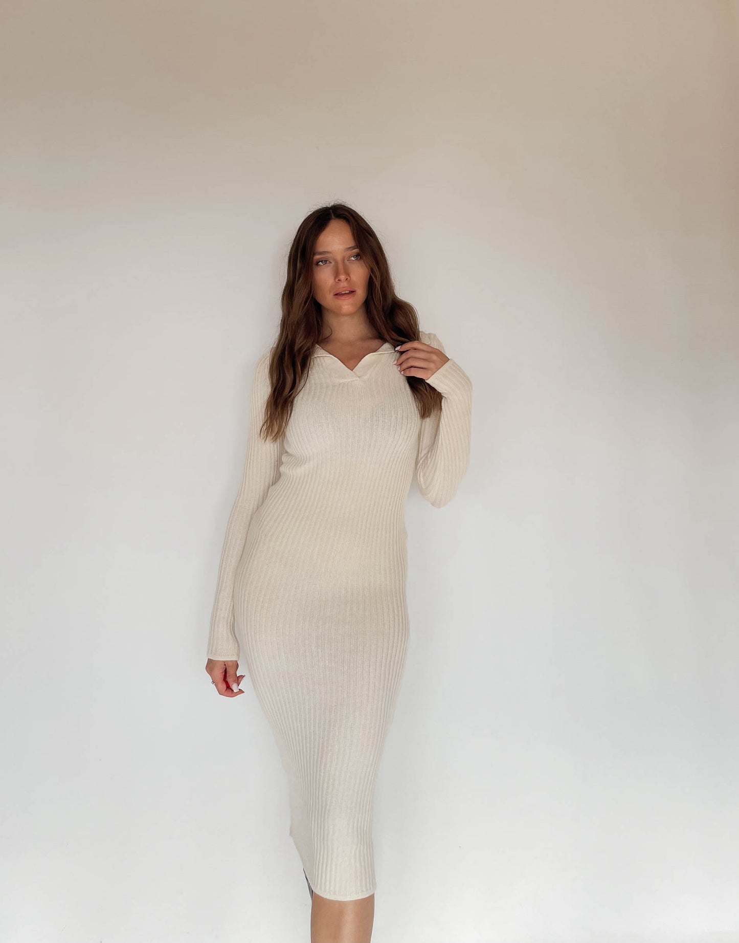 Frau mit brauen Haaren trägt Strickkleid in Beige