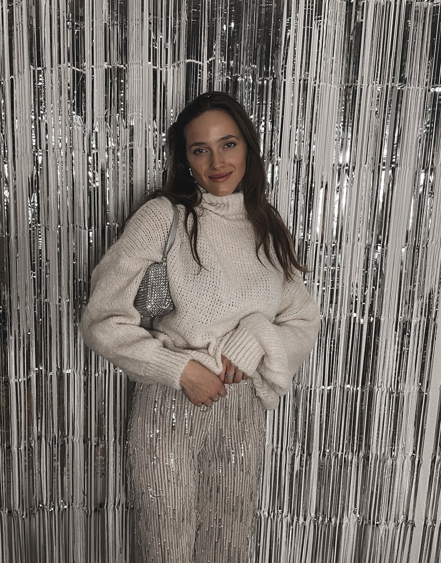 Frau mit brauen Haaren trägt Glitzerhose in Beige mit Strickpullover